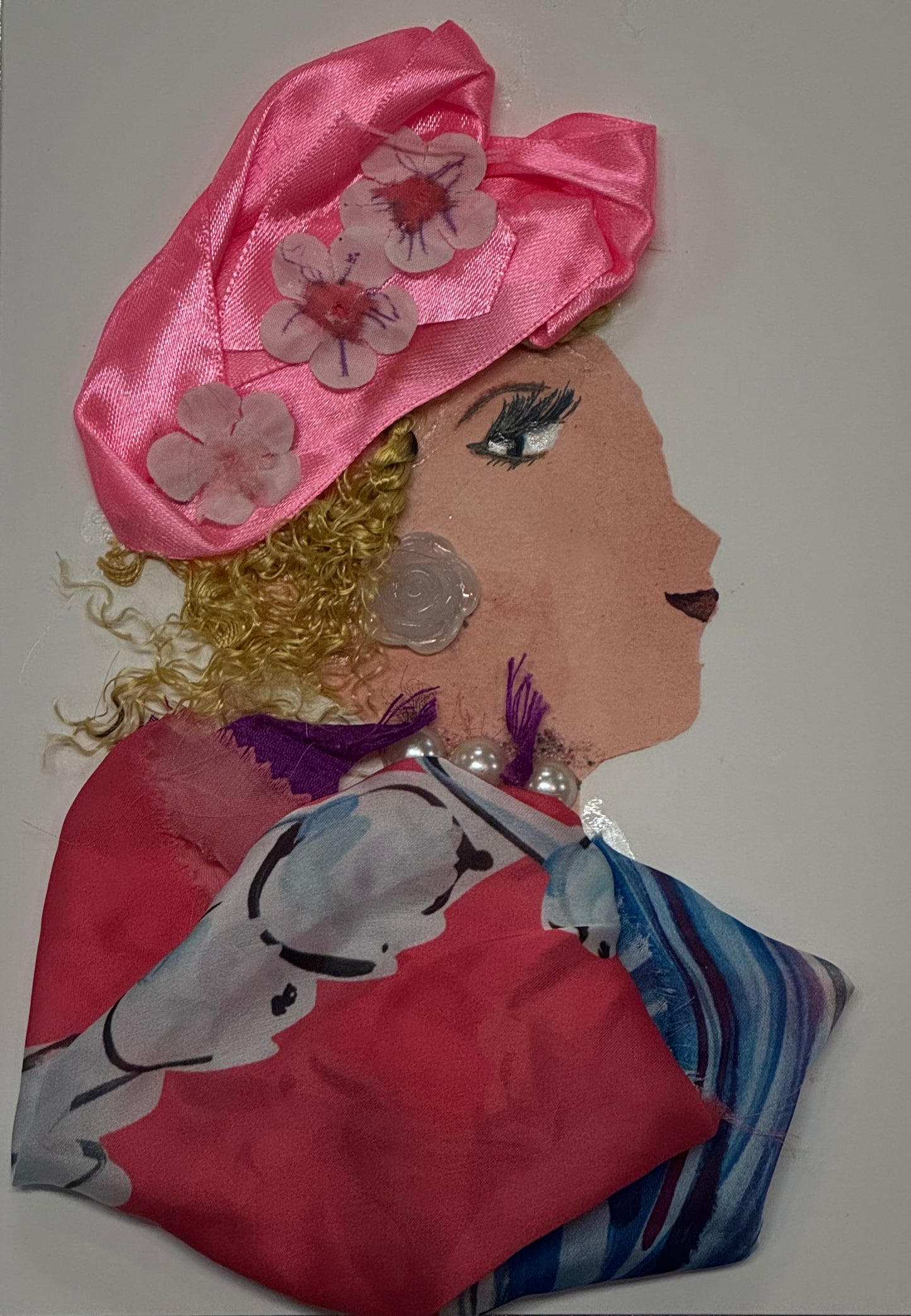 Handmade card that can double as a piece of art featuring a stylish woman with curly hair wearing a large pink hat decorated with flowers. She wears a soft pink satin outfit with a flowing scarf and pearl jewelry. The background is light and minimal, highlighting the delicate floral details and elegant spring theme.