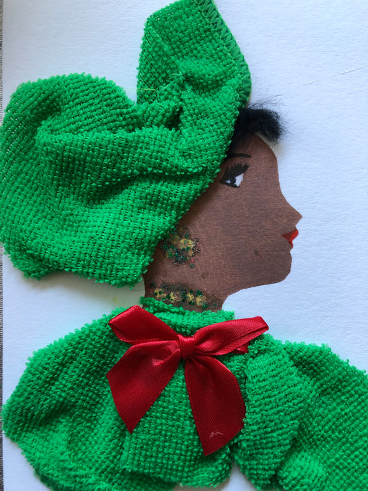 Handmade card showing the side profile of a woman with textured black hair and a bold red lip. She wears a large green textured headwrap and a matching green outfit, accented with a red ribbon bow at the neck. Glitter details decorate her earring and neckline. The background is plain white.