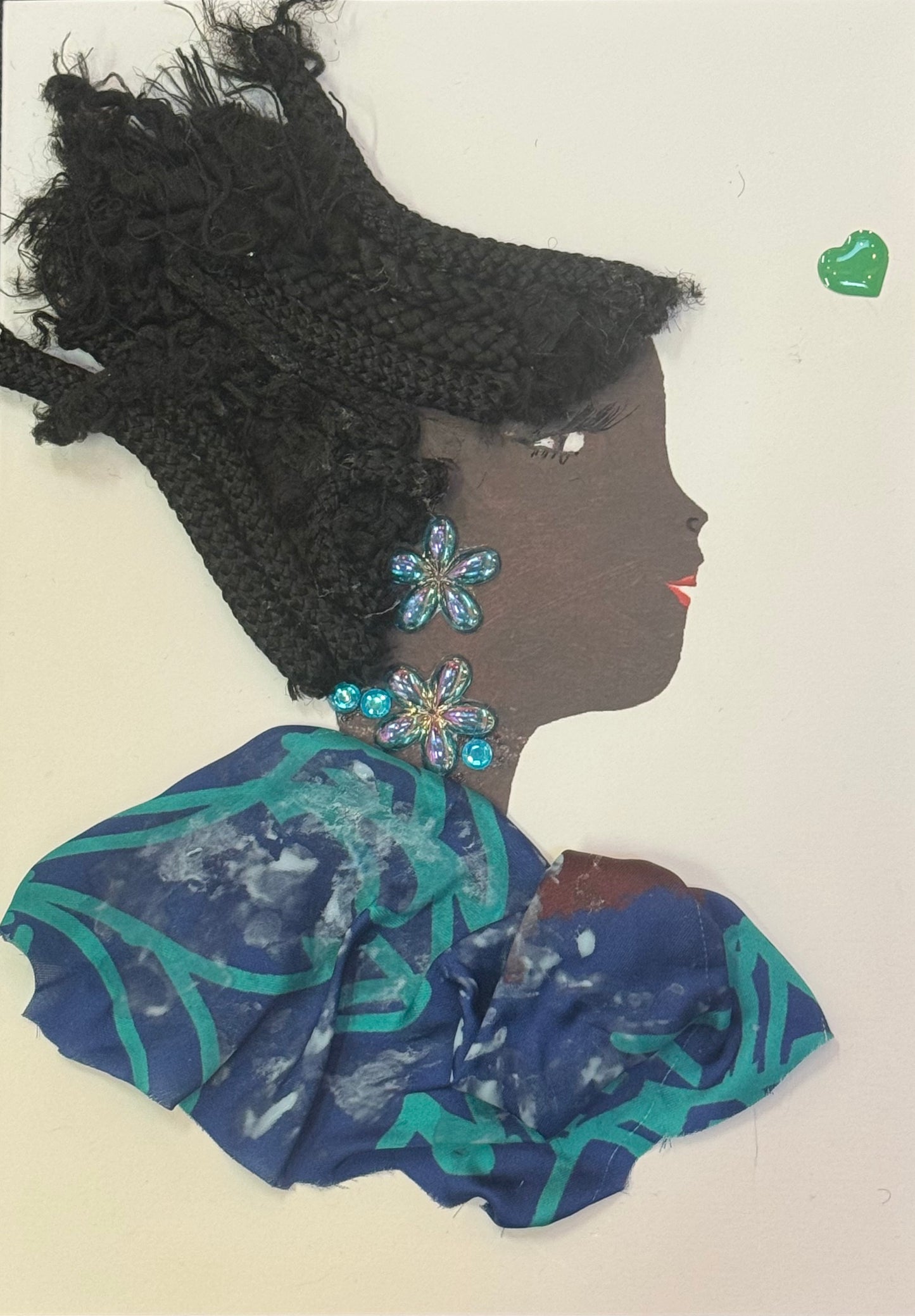 Handmade greeting card that can double as a piece of art featuring a side-profile of a woman with a dark skin tone and textured natural hair styled upward, wearing blue and teal patterned clothing with large floral gem earrings. Also featured is a small detailed green heart on the right side of card.