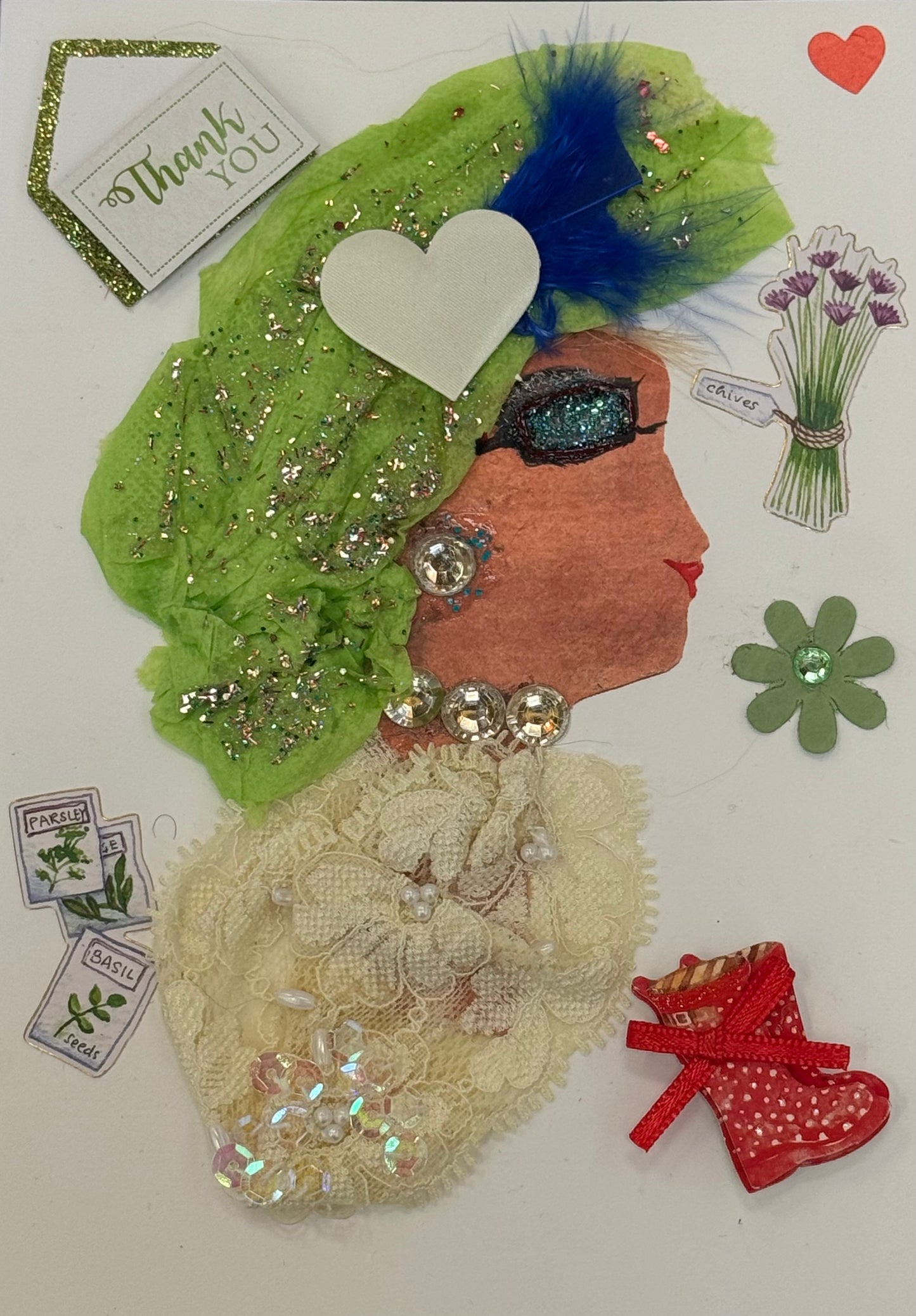 Handmade collage greeting card featuring a right-facing side profile of a woman with medium-brown skin. She wears a bright green textured headwrap decorated with scattered glitter and a prominent blue feather accent on the side. Her makeup includes shimmering blue eyeshadow, thick lashes, and bold red lips. She is adorned with large rhinestone-style earrings and a matching necklace with reflective, faceted elements.