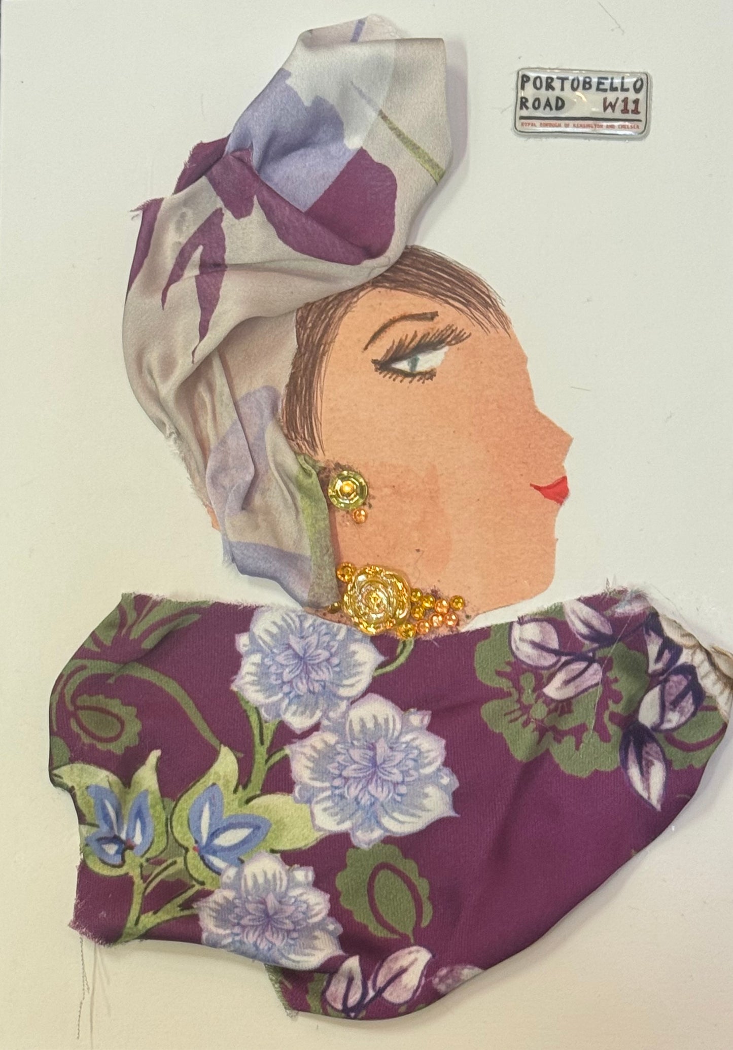 Handmade greeting card that can double as a piece of art featuring a side-profile collage of a woman wearing a floral purple blouse and a complimenting patterned headscarf, with gold earrings and a visible “Portobello Road” sign charm in the right corner of card.