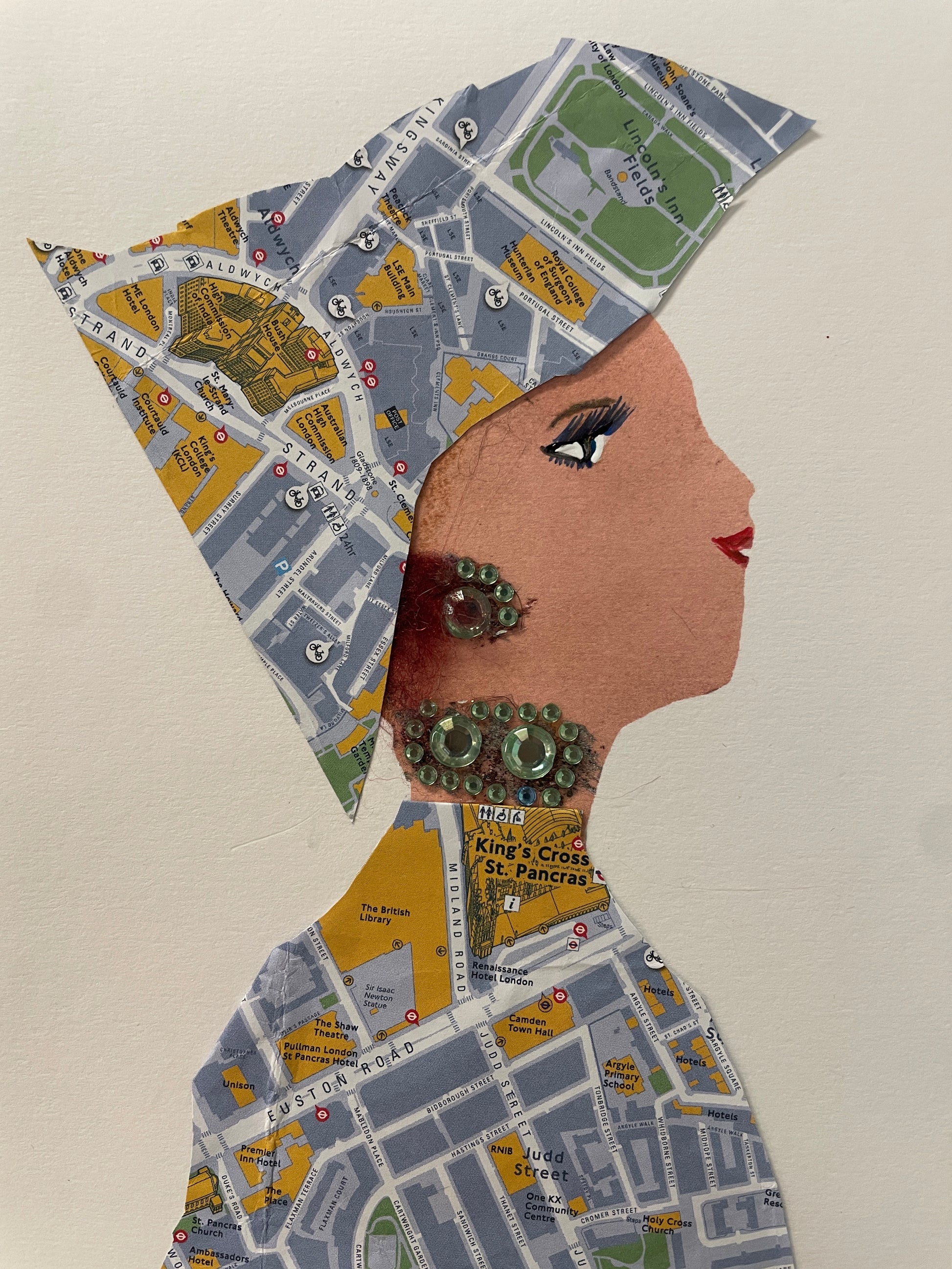 This is a handmade card of a woman named Amara Kingsley dressed in map-printed fabric with green round earrings and gems, her wrap and blouse made from pieces of a London map.
