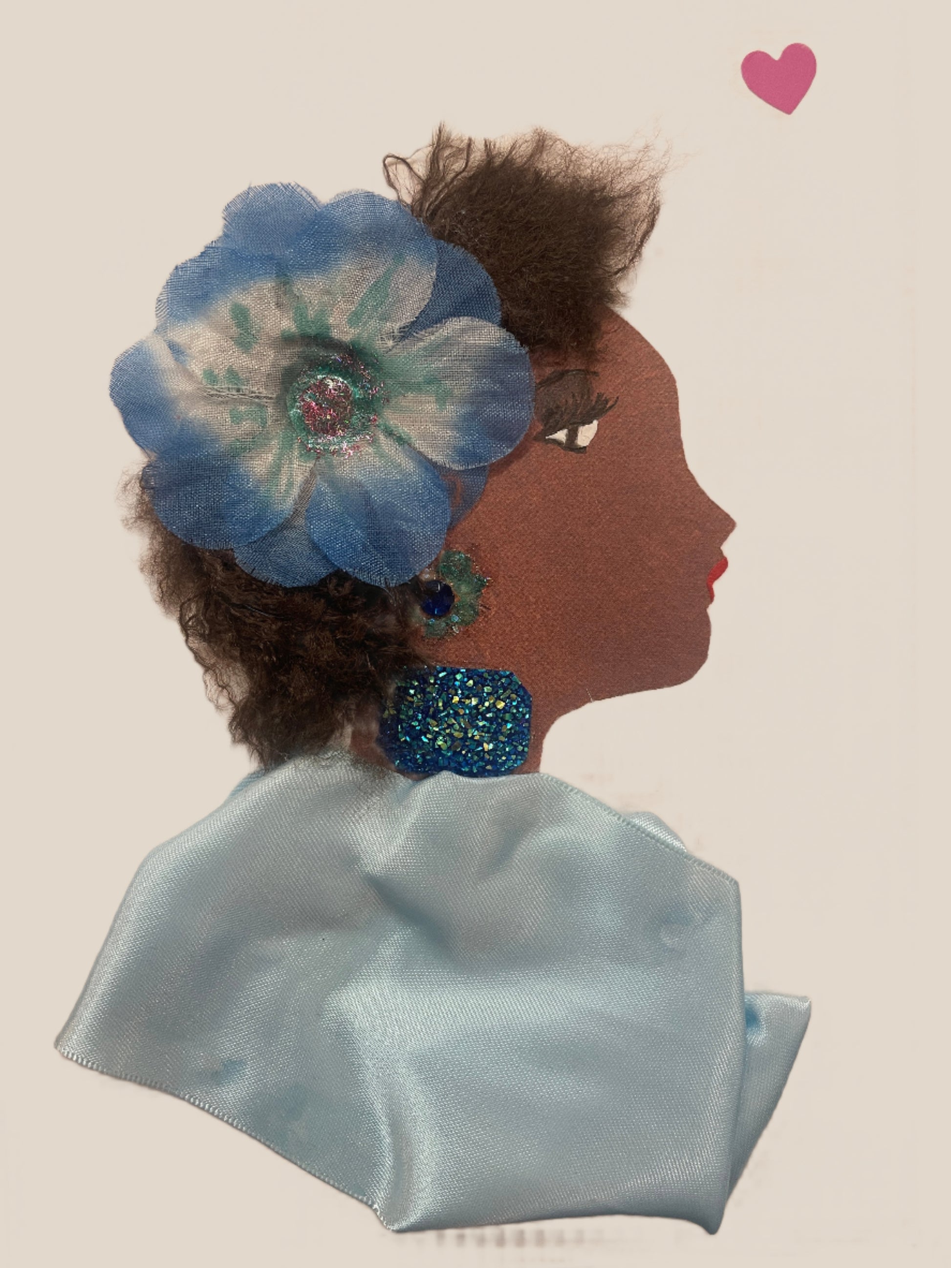 This is a handmade card of a woman named Azure Abbey. She has a large blue flower in her hair, textured dark curls, glittering teal jewellery, and a silky light blue wrap. A small pink heart is in the top right corner.