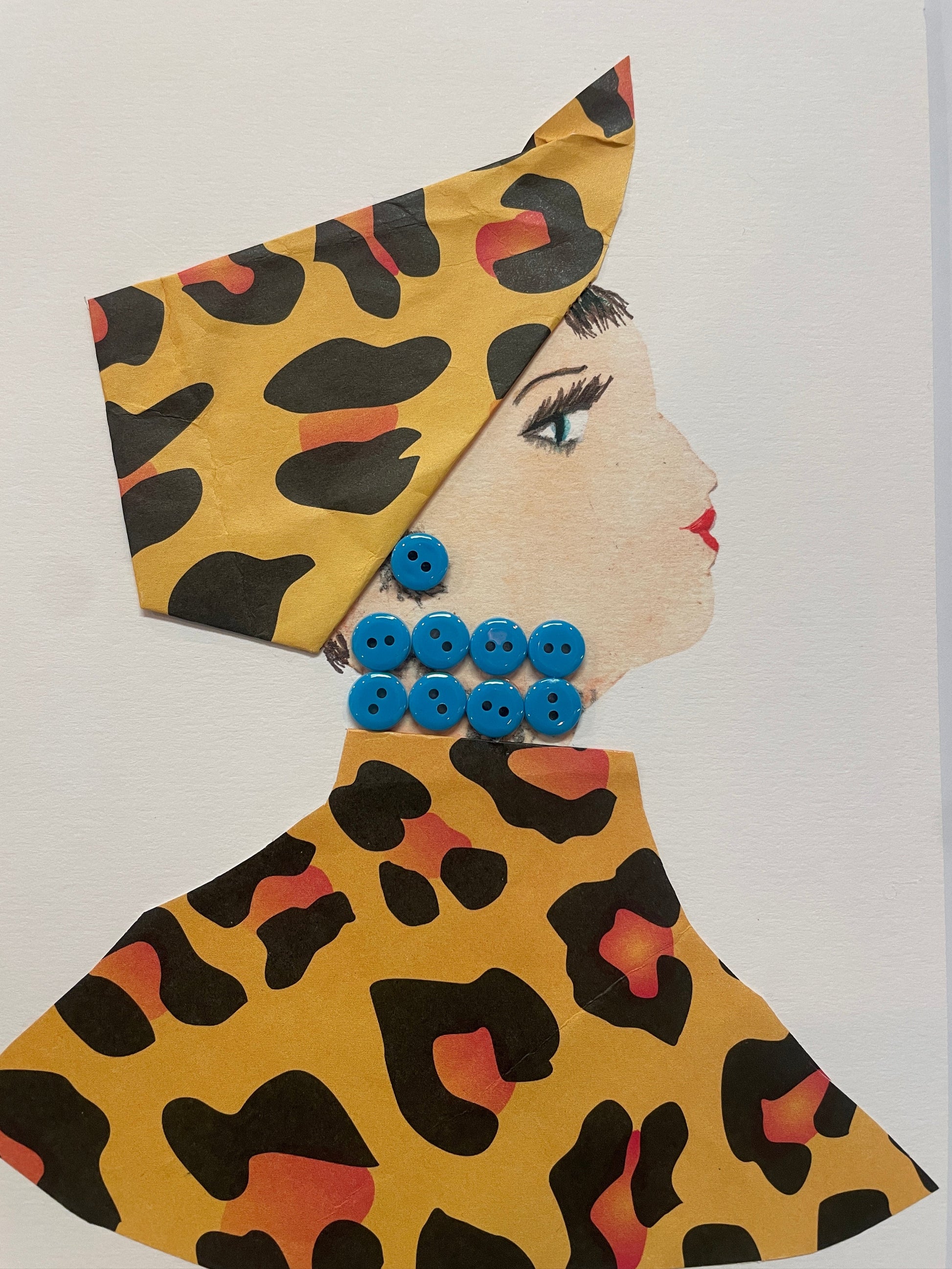 A handmade card of a woman named Bluebell Bea in profile wearing yellow leopard print clothing and a headwrap, accessorised with round blue buttons for earrings and necklace.
