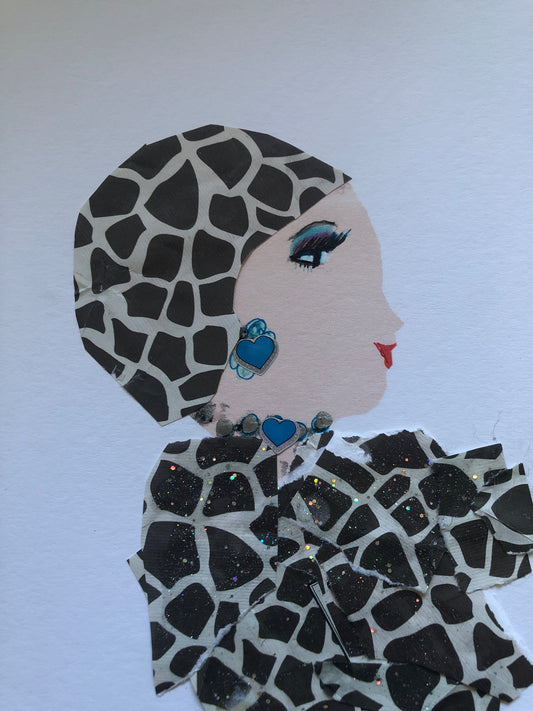 I handmade this card of a woman named Brilliant Peterlonia. She’s shown in profile with striking eye makeup, red lips, and a confident expression. Her outfit and headwrap are made from matching giraffe-print fabric with added sparkle. She wears a blue heart-shaped earring and a necklace with matching blue accents.