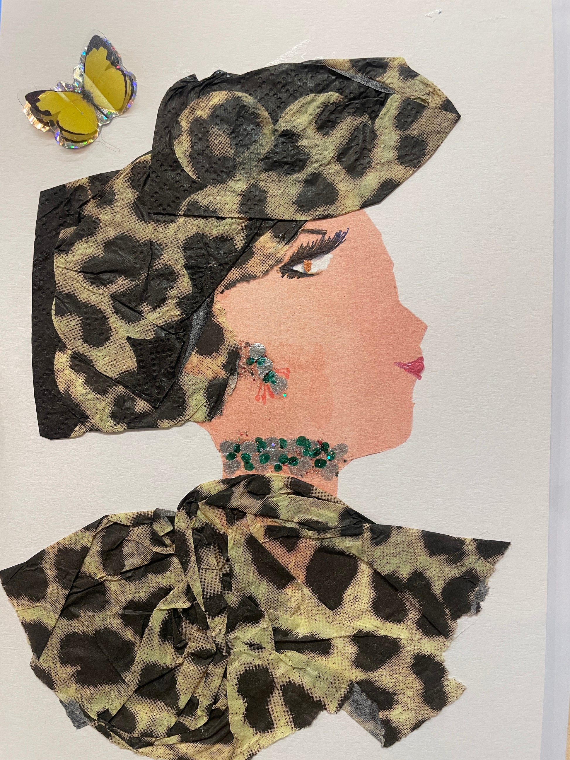 A handmade card of a woman named Butterfly Brixton in profile dressed in greenish leopard fabric with a matching headwrap. She wears green and silver jewellery, with a yellow butterfly sticker in the corner.