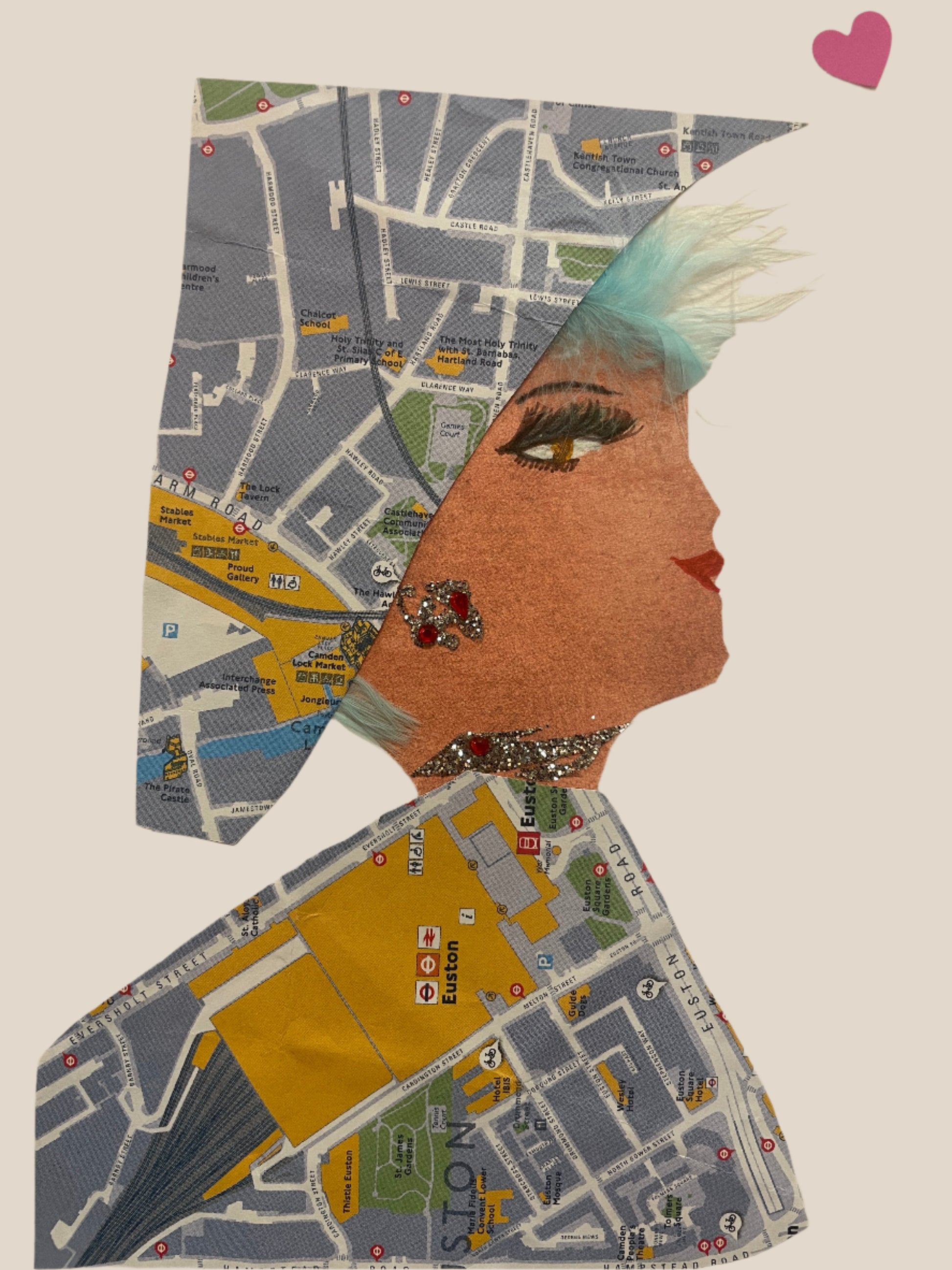 This is a handmade card of a woman named Camden Ashby. She wears a wrap and dress made of a detailed printed London map. Her look is finished with red gemstone earrings and necklace, a teal feather fringe, and a pink heart sticker floating above her head.
