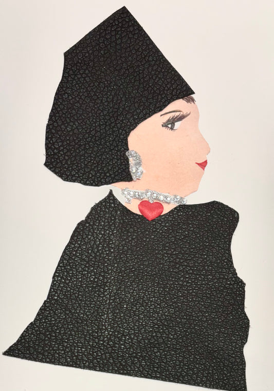 A woman wears a matching black textured hat and blouse. She wears a sparkly silver earring and necklace with a red heart in the middle.