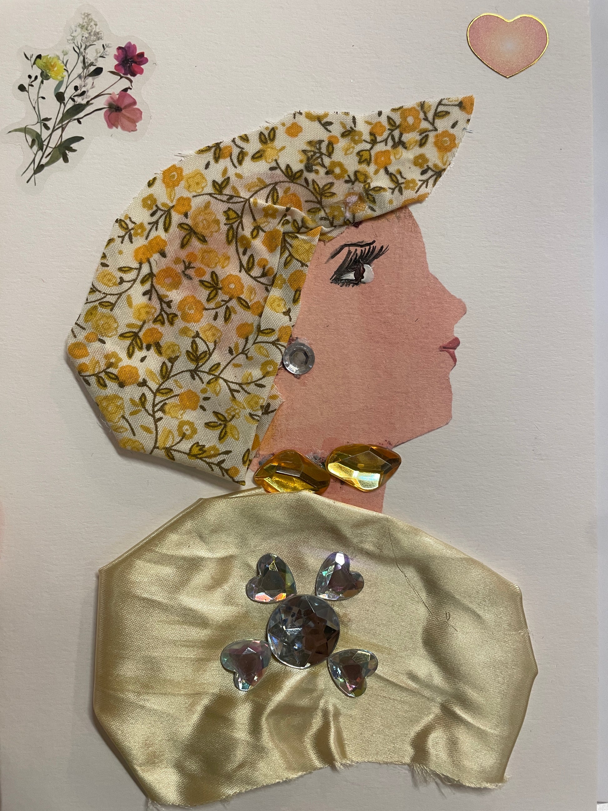 This is a handmade card of a woman named Dynamic Daisy. She wears a yellow floral headwrap and pale yellow satin top, decorated with large rhinestones. There are floral and heart stickers in the background.