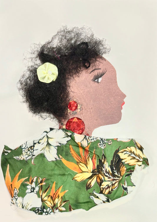 This is a handmade card of a woman named Elderflower Emily. Her hair is made from soft, textured fibres and decorated with a pale yellow flower. She wears large red gem earrings, and her outfit is created from green fabric with a tropical floral print in white, yellow, and orange. Her face is drawn in profile with calm features and red lips.