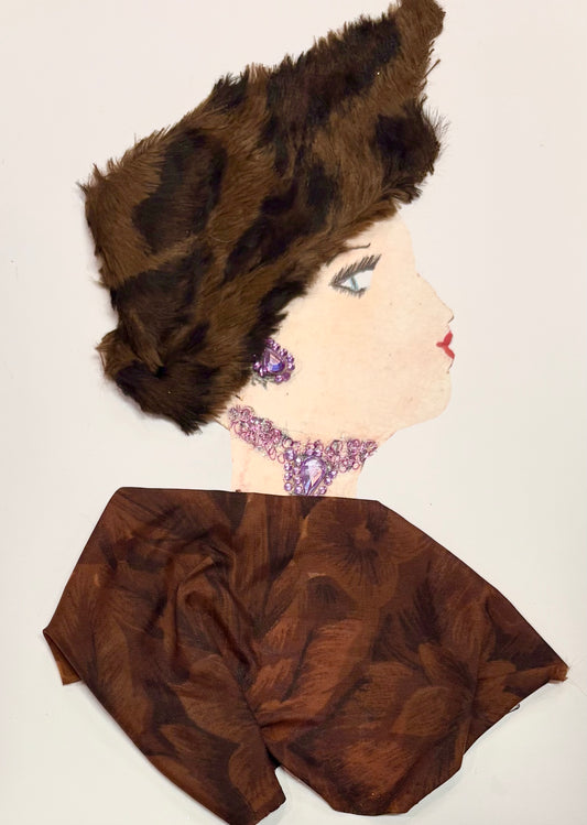 This is a handmade card of a woman named Embankment Ella. She wears a sculptural faux fur hat in rich brown with black accents, styled high and dramatic. Her earrings and necklace are made from purple gemstones, with the necklace forming a striking cluster at the base of her neck. Her outfit is a smooth, chocolate-brown fabric with a dark floral pattern, giving a classic and composed finish.