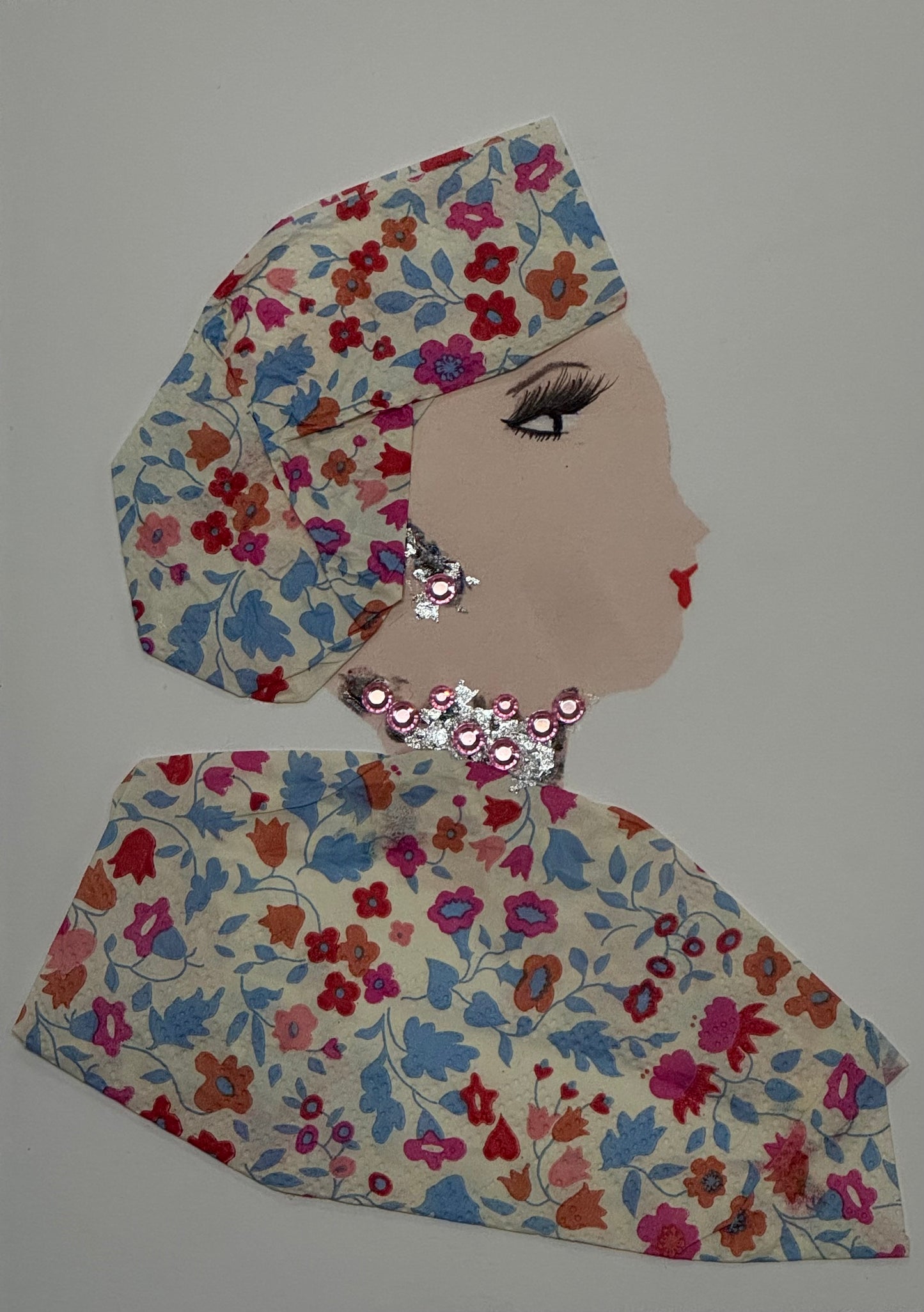 Handmade card that can double as a piece of art, featuring a woman wearing a patterned headscarf tied around her hair with a matching blouse and a large pink and silver jeweled necklace. She also wears a matching set of earrings. The design has a vintage-inspired style with decorative textures and subtle pastel colors.