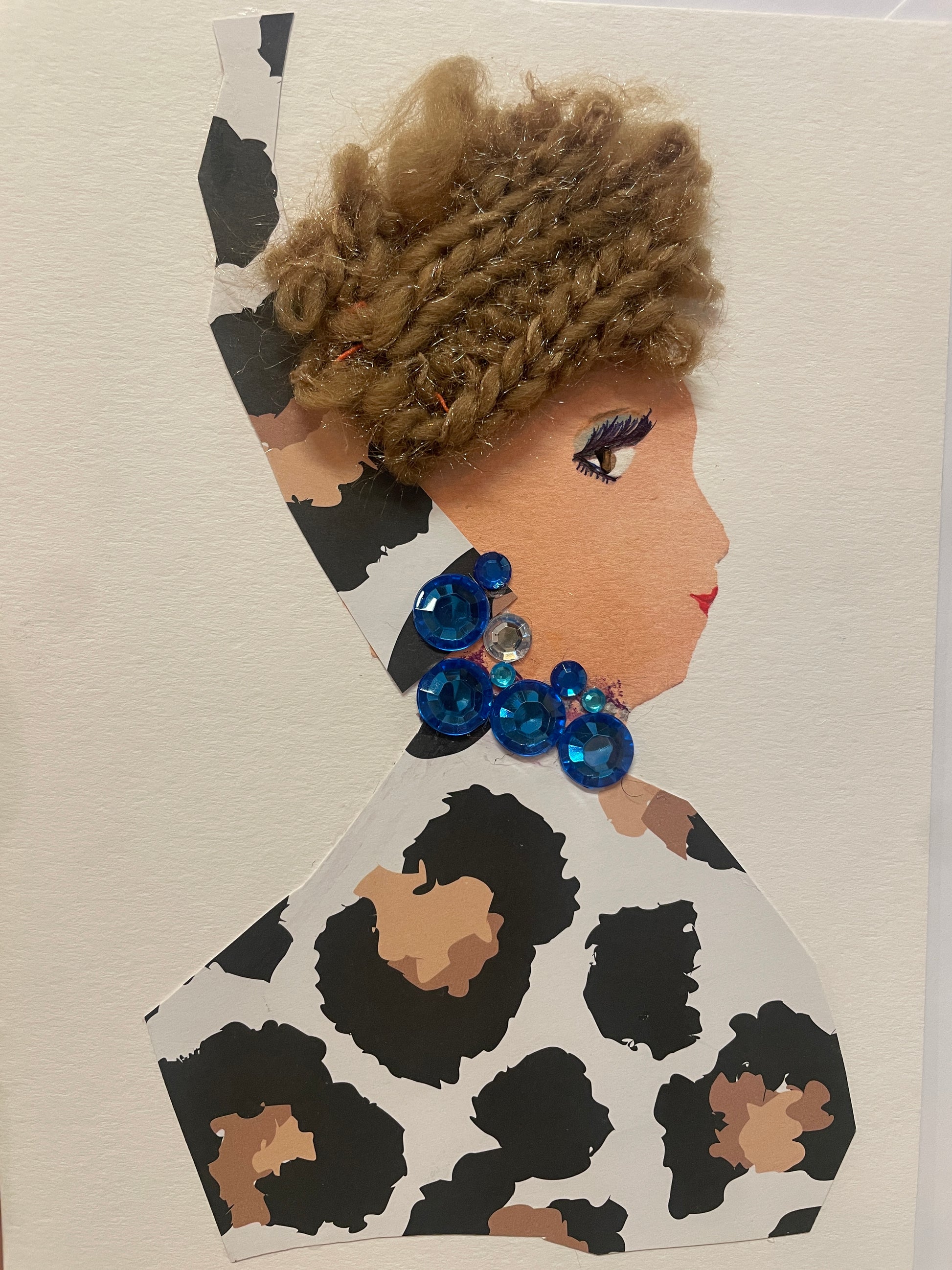 This is a handmade card of a woman named Giovanna Greatness, wearing a leopard-print outfit and head wrap with a brown braided hat, and large bright blue gem earrings and necklace.
