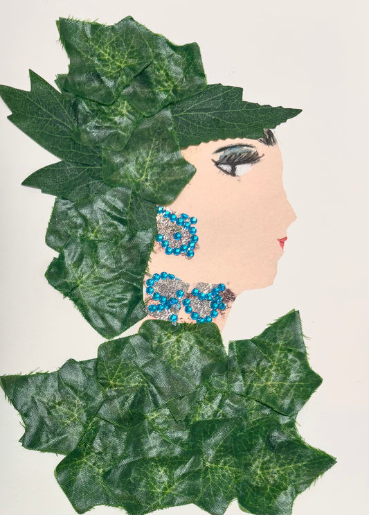 A woman wears leaves as a hat with a matching leaf blouse. Her jewellery is sparkling silver with little blue gems.