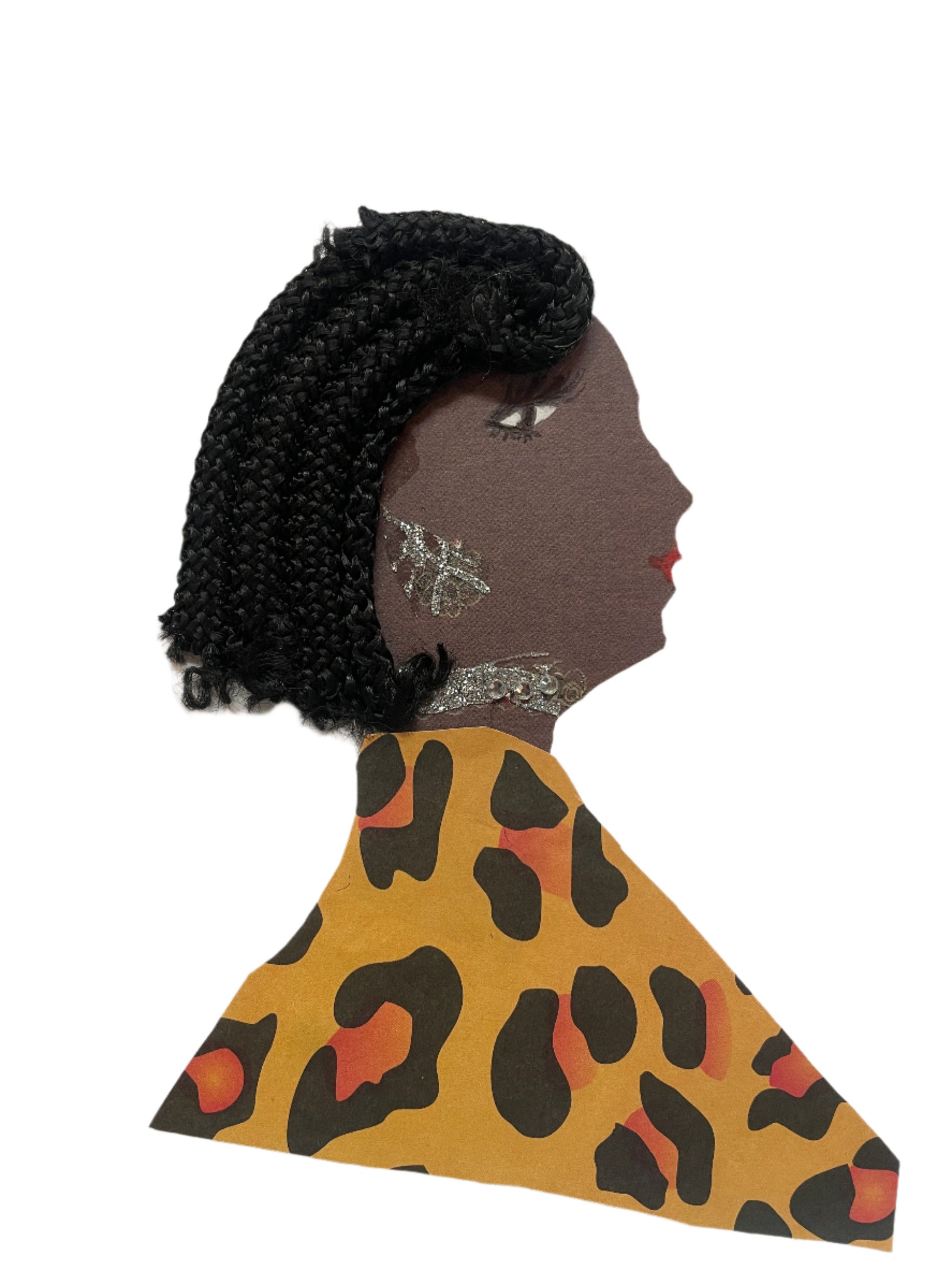 A handmade card of a woman in profile wearing yellow-orange leopard print fabric and a black braided hairstyle. She wears silver sparkly earrings and a necklace.