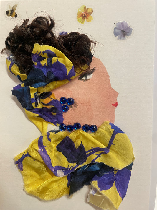 This is a handmade card of a woman named Zadie Zinnia. She wears a yellow and violet floral wrap around her hair and shoulders, accented with blue gems. Background includes three small flower stickers.