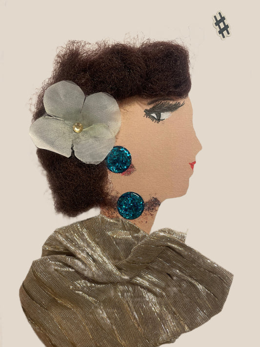 This is a handmade card of a woman named Claire Chiswick. She wears a soft gold pleated wrap and teal glitter earrings, with a white flower clipped into her curly hair. A small black sticker shaped like a hashtag is in the corner.