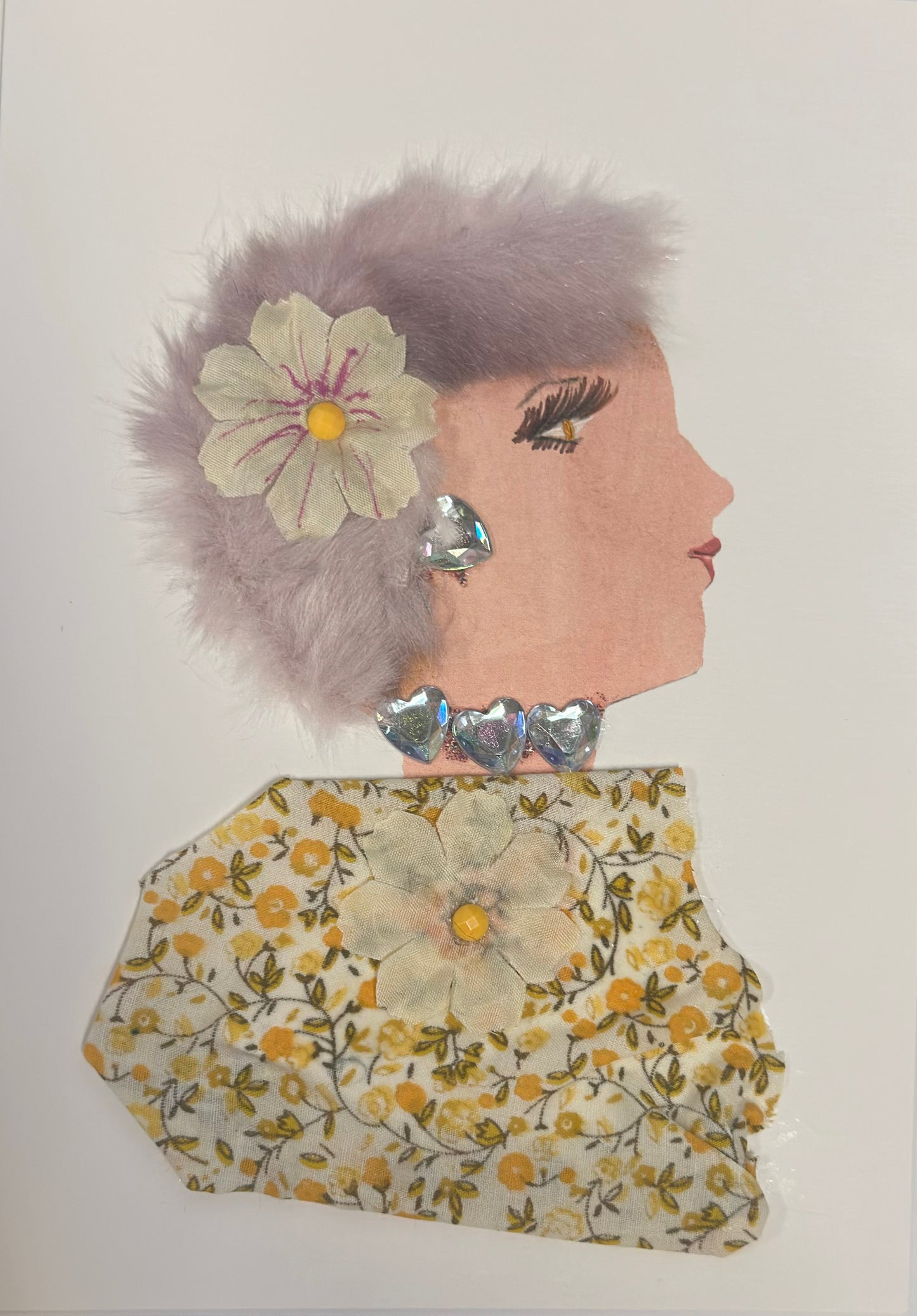 A handmade card shows a side-profile portrait of a woman with pale skin, soft lavender fluffy hair, and pink lips. She has a cream flower in her hair, iridescent heart-shaped earrings, and a silver heart choker. Her dress is made of yellow floral fabric with a matching flower embellishment in the center.