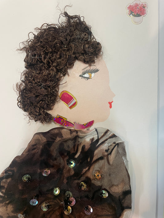 This is a handmade card of a woman named Lorna Lavenderhill. She has curly brown hair, wears pink gem jewellery, and a brown blouse with a natural pattern and extra sparkly gems. A flower sticker is in the top right corner.