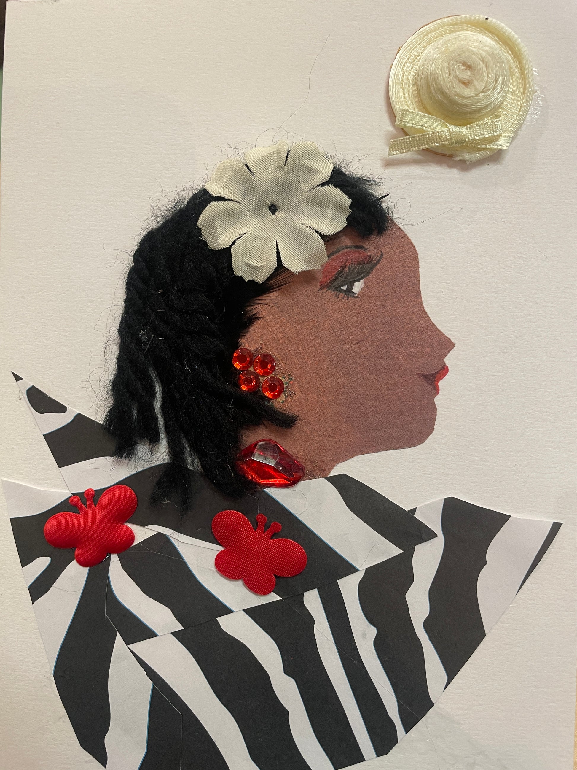 This is a handmade card of a woman named Tilda Tufnell. She wears a zebra-print blouse with red butterflies, short black hair with a white flower, and large red gem jewellery. There’s a small hat sticker in the background.