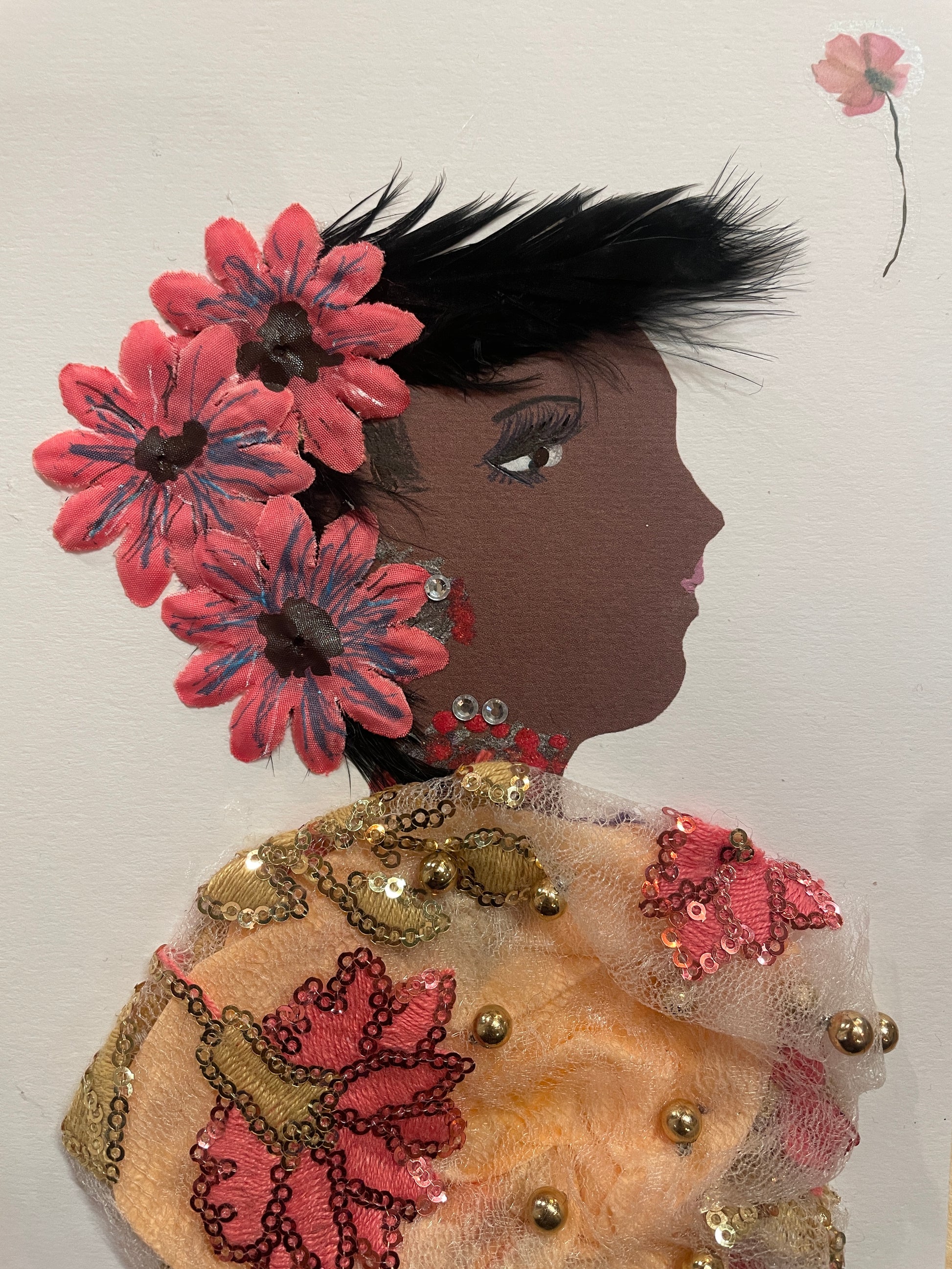 This is a handmade card of a woman named Orla Old Kent. She wears an orange and cream floral blouse, soft pink flowers in her straight black hair, and red jewellery. A flower sticker is in the top right corner.