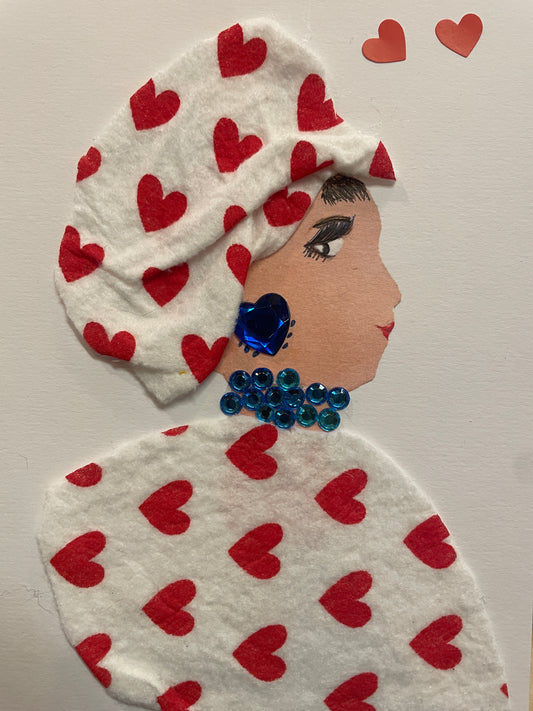 This is a handmade card of a woman named Elowen Eltham. She wears a white top with red hearts printed on it, blue gem jewellery, and there are two red heart stickers in the corner.