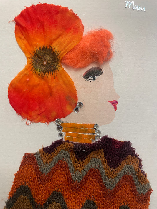 This is a handmade card of a woman named Marigold Mile End. She wears a fall-coloured knitted zig-zag blouse, a large orange hat, has orange hair, and the word “MUM” appears in the corner.