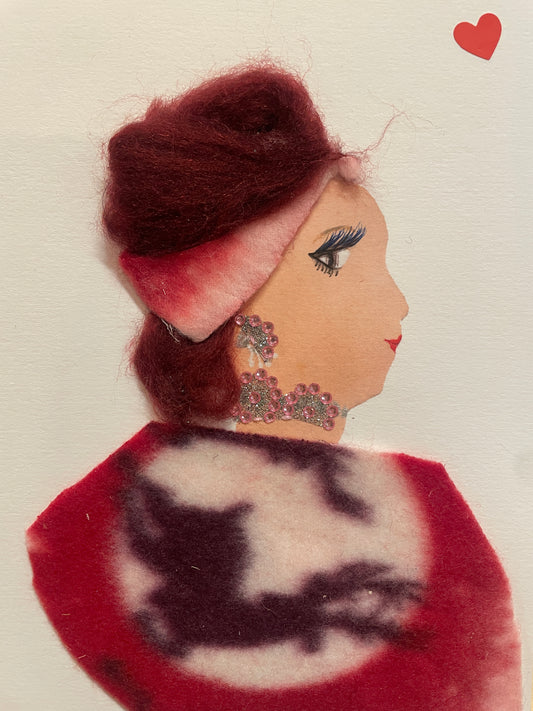This is a handmade card of a woman named Rosetta Ravenscourt. She wears a red blouse and red hat, has fluffy red hair, silver jewellery, and a red heart sticker in the corner.