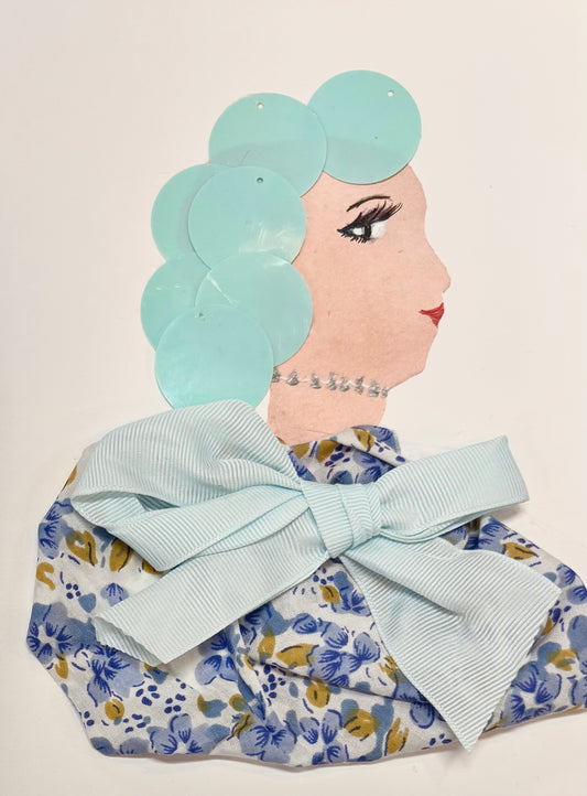 A side profile of a woman's face made with mixed materials. Her hair is created from light blue circular pieces, and she wears a silver beaded necklace. Her outfit features a floral fabric in blue, white, and yellow, topped with a large light blue ribbon bow. Her eye and lips are drawn on.