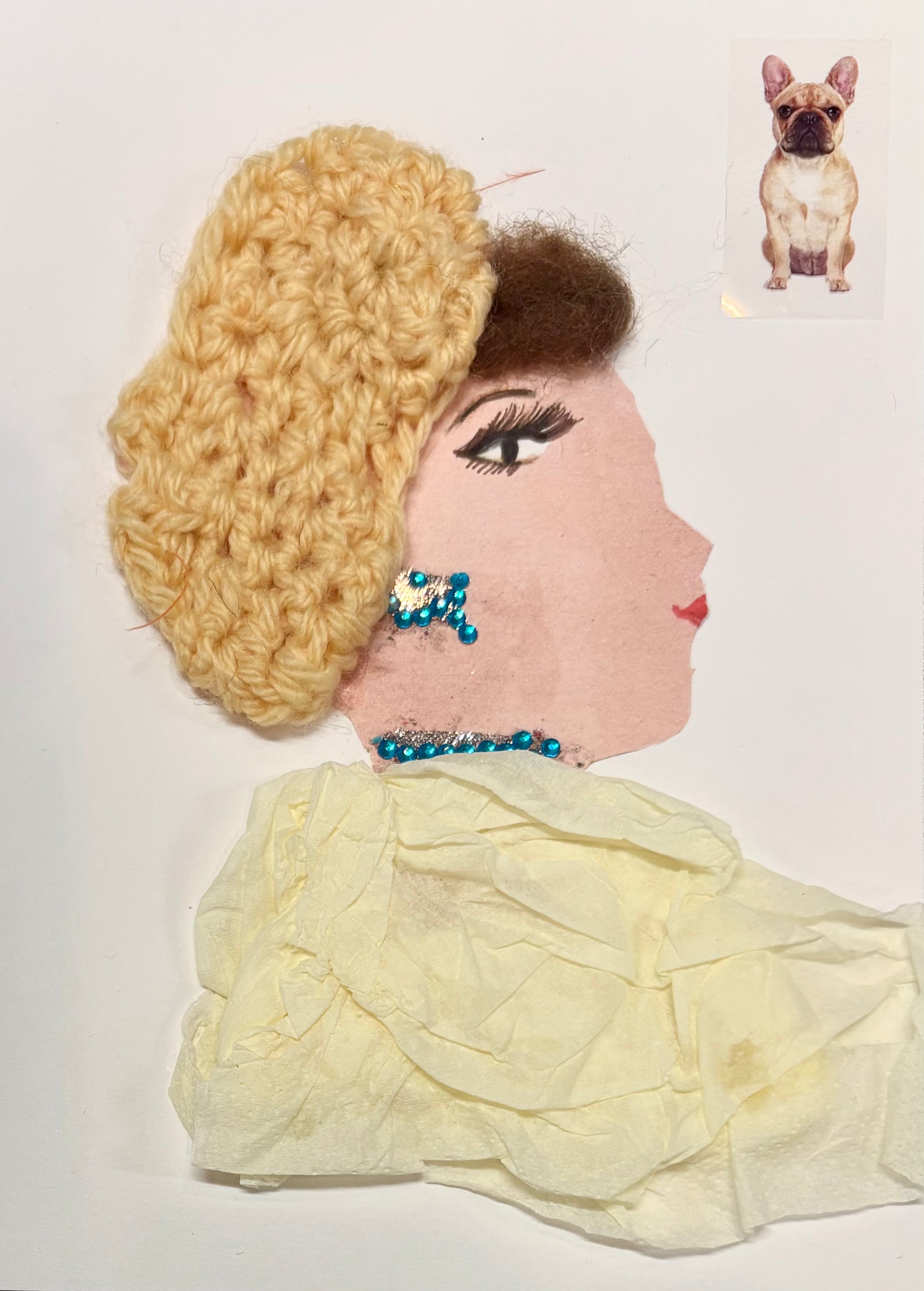 I handmade this card of a woman named Yellow Iris. She’s shown in profile with drawn lashes, red lips, and a voluminous blonde crochet headwrap. Her jewellery sparkles with turquoise blue and silver embellishments on her ear and neckline. She wears a soft, crinkled yellow garment, and a sticker of a French bulldog sits nearby.