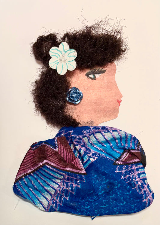 A side profile of a woman created with mixed materials. She has curly dark hair decorated with a white and teal flower clip. A shiny blue rose earring is on her ear. Her outfit is made from a bold blue fabric with purple, pink, and maroon patterns. Her eye and lips are drawn on.