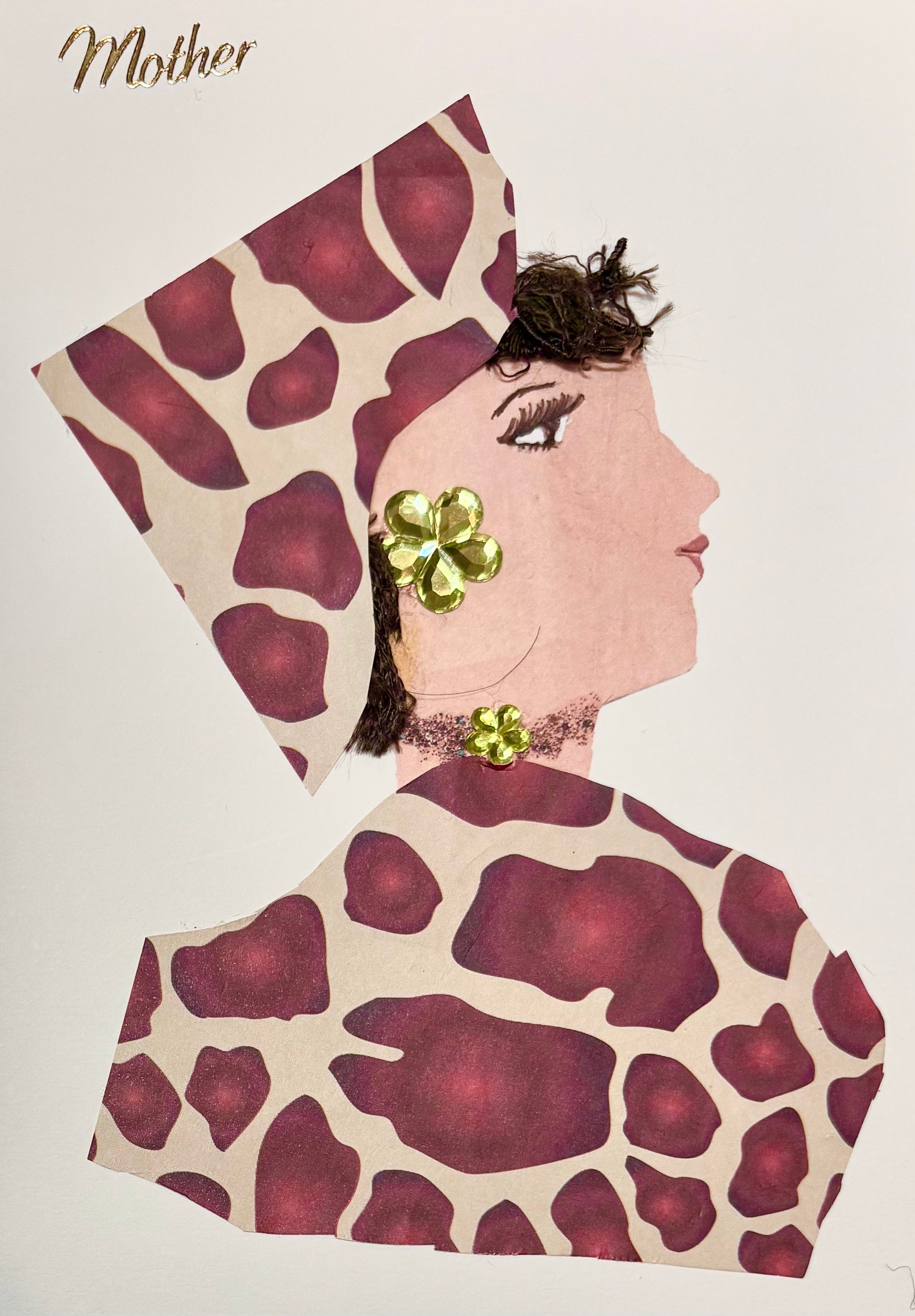 I handmade this card of a woman named Lady Chiswick. She’s shown in profile, with soft makeup, and textured dark brown hair. Her outfit and headwrap are made from a bold maroon-and-cream animal print. She wears shiny green floral earrings and a matching embellishment at her neck. The word “Mother” is written in gold script above her.