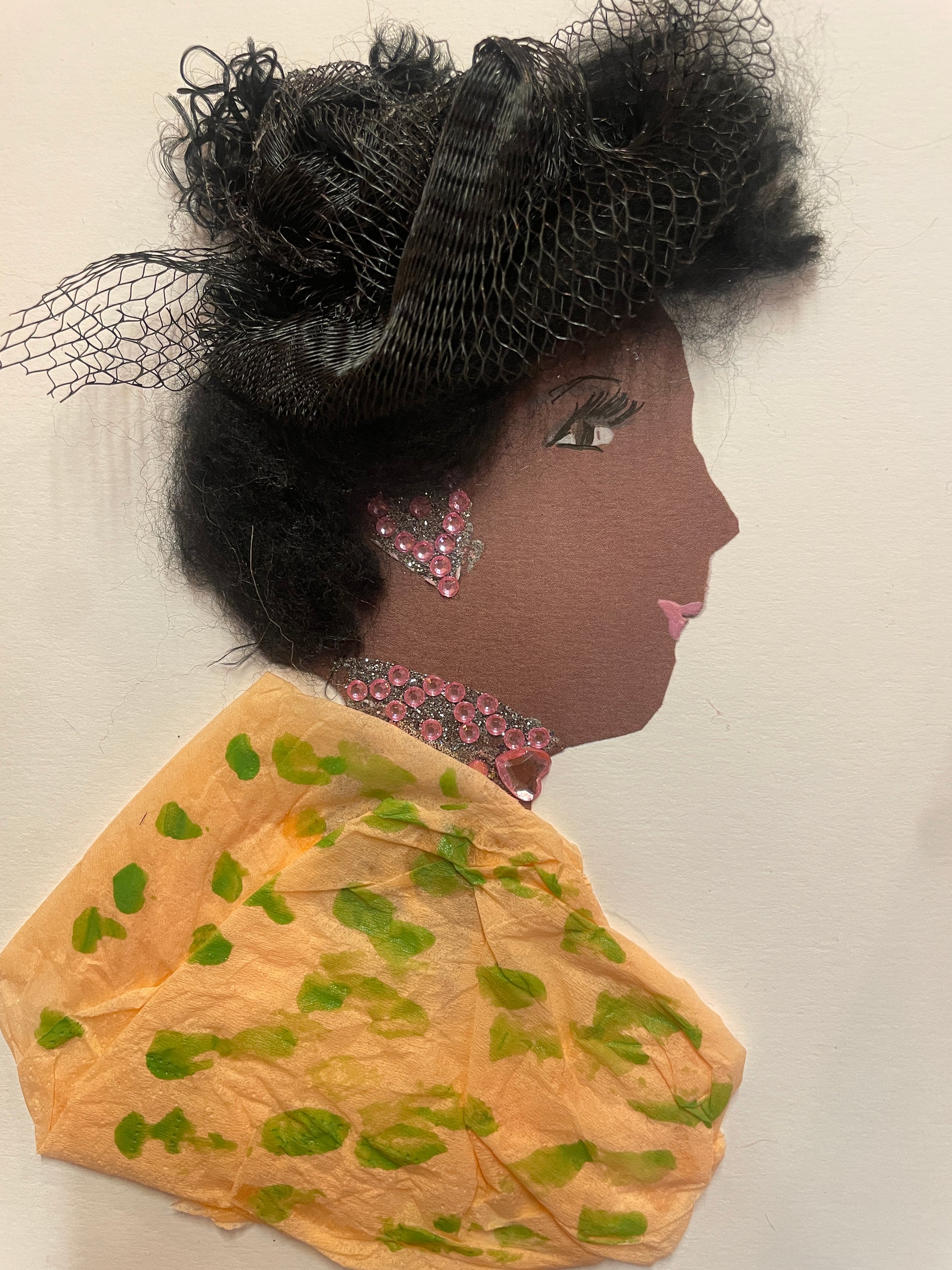 A handmade card of a woman wearing a textured black netted headpiece and a soft orange outfit with green blotches. She has a pink beaded necklace and matching triangle earring.