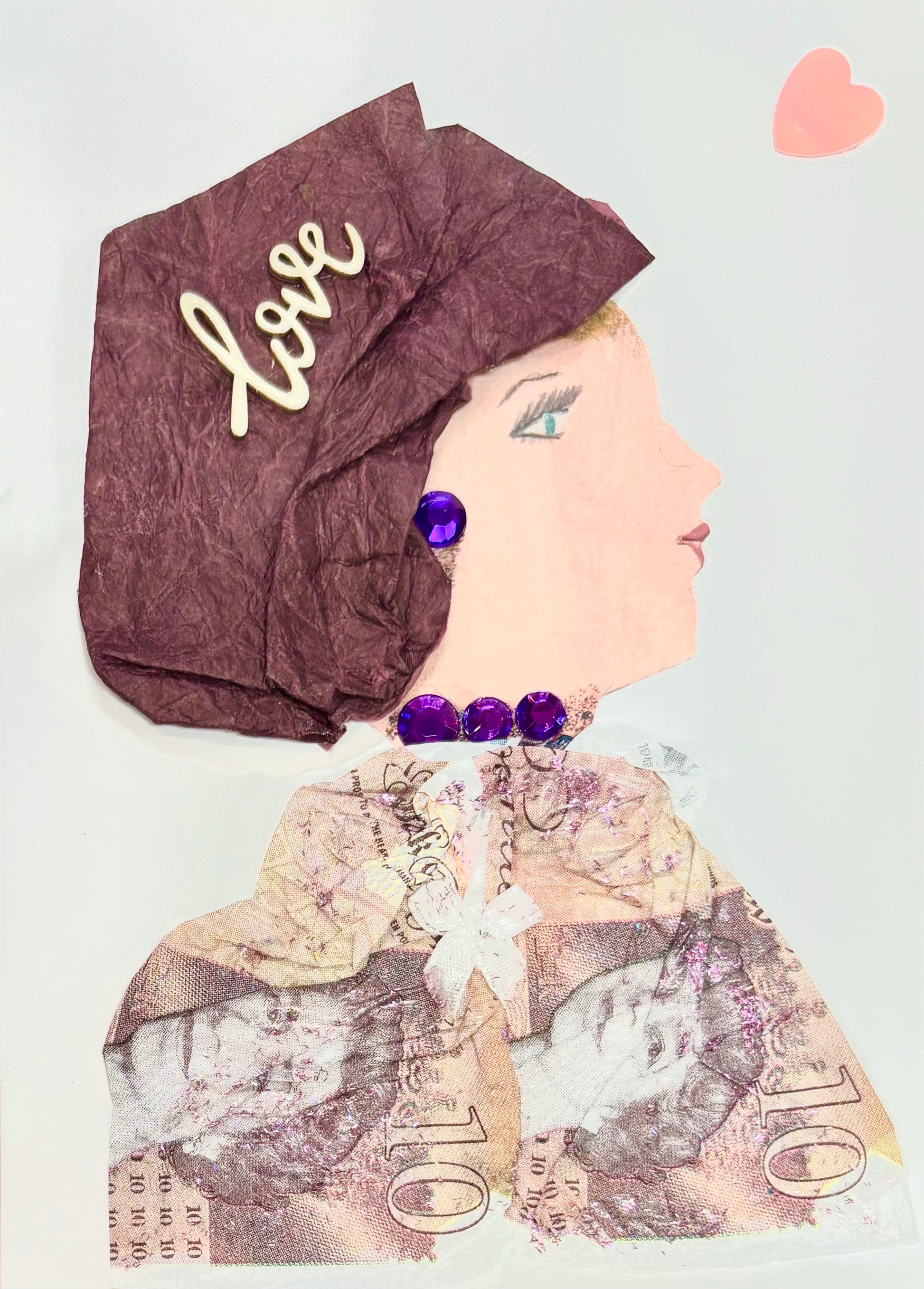 A handmade greeting card featuring a woman in profile, wearing a deep purple headwrap with the word “love” on it. Her outfit is made from printed £10 notes, and she is adorned with purple gem jewellery and a white bow. A small pink heart floats nearby.