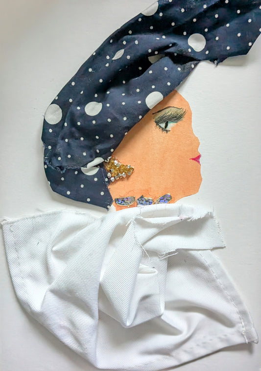 I handmade this card of a woman named London Lisa. She’s shown in profile with bright pink lips, bold eyeliner, and a confident gaze. Her headwrap is made from navy blue fabric with scattered white polka dots, and she wears sparkly gold and crystal-like earrings. A shimmering detail wraps around her neck, and her crisp white outfit is fashioned from folded cloth.