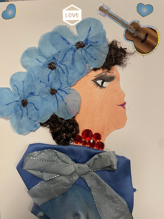 Handmade card of a woman with curly hair, blue floral headwrap, red gemstone necklace, and a blue satin dress with blue bow. A guitar and hearts decorate the background.