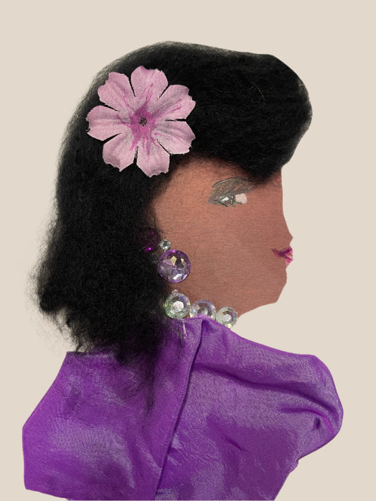 Handmade card showing a woman in profile with voluminous black hair, a pink flower accessory, and large iridescent gem earrings and necklace. She wears a shiny purple dress.