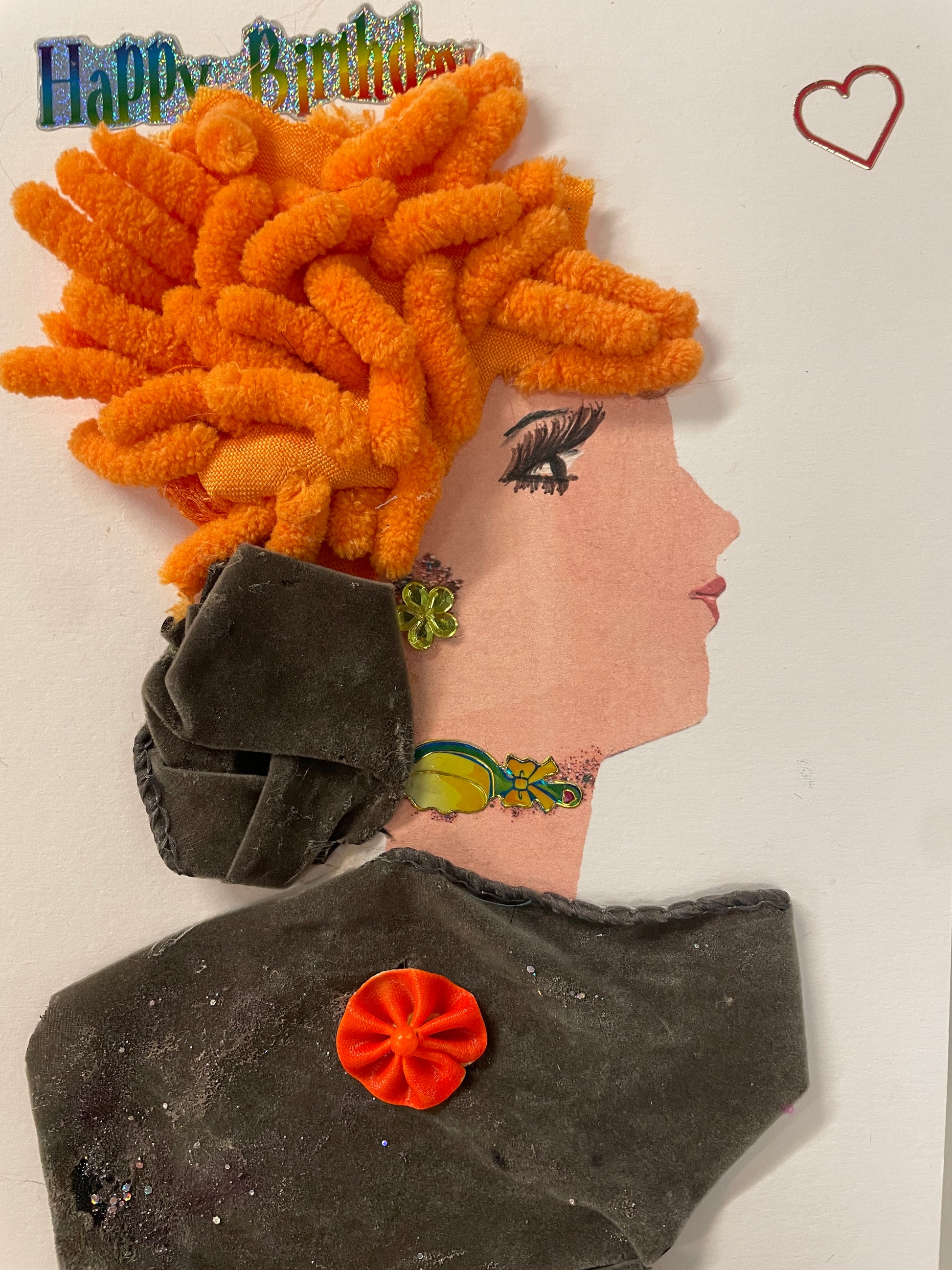 This is a handmade card of a woman named Mavis Bright with vivid orange curly hair, a green earring, and a fuzzy grey velvet dress, with a "Happy Birthday" sticker and a heart above.