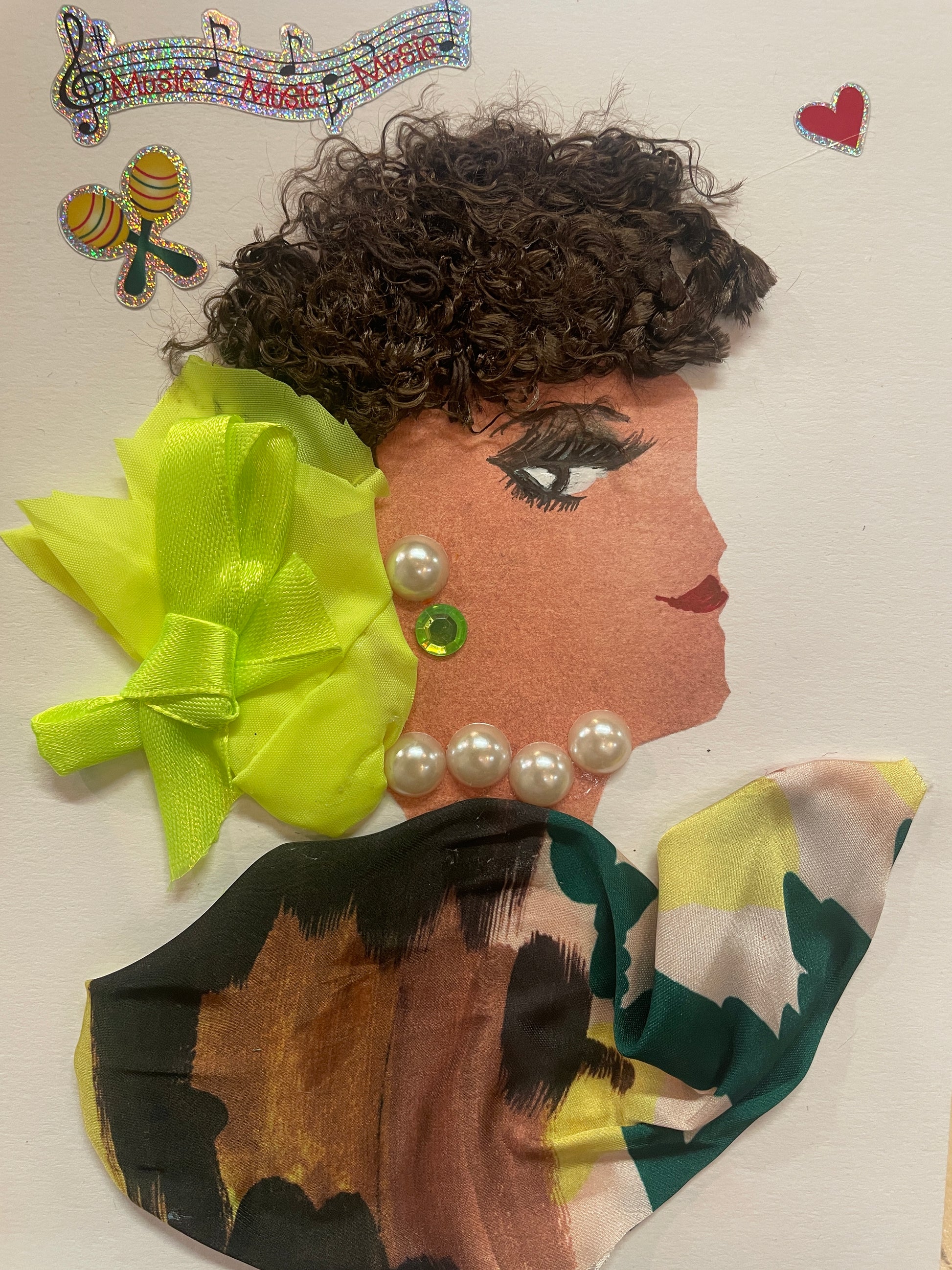 This is a handmade card of a woman named Melody Millwall. She has short, curly dark hair with a bright yellow bow and wears a pearl necklace and a patterned blouse in green, brown, and yellow tones. A green gem earring sparkles at her ear. In the background, there are holographic stickers of musical notes, a pair of maracas, and a small red heart.