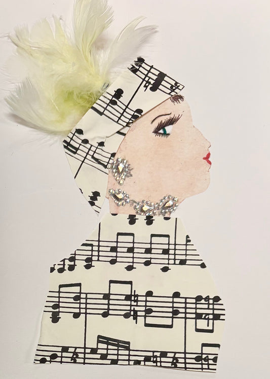 I handmade this card of a woman named Melody Music. She’s shown in profile with defined lashes, red lips, and a serene expression. Her headwrap and outfit are made from sheet music paper, and pale yellow feathers plume from the top of her wrap. She’s adorned with glittering silver rhinestones as earrings and at her neck, echoing her elegant, melodic style.