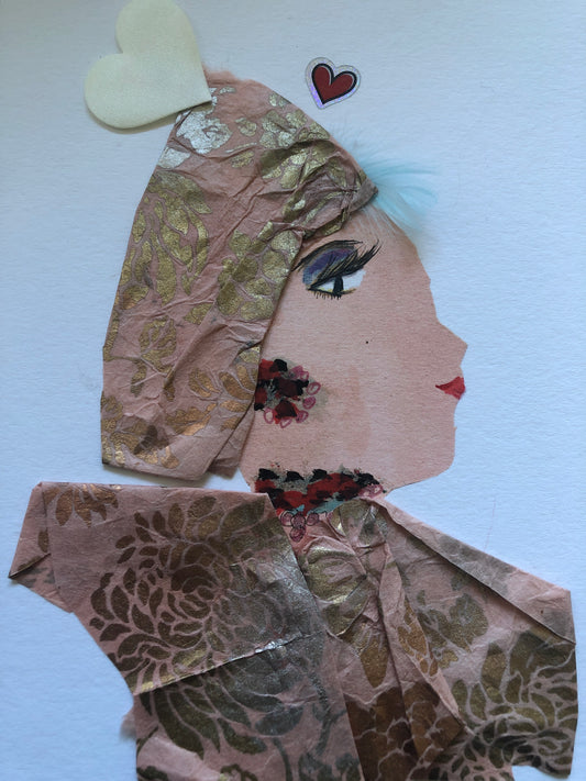 This is a handmade card of a woman named Millie Marvelous. She wears a soft pink outfit and headwrap, both decorated with gold floral patterns. She has a small patch of blue feathers as hair, and her earrings and necklace are made from flower shapes in shades of red and black. Two hearts float above her head—one white and one red.