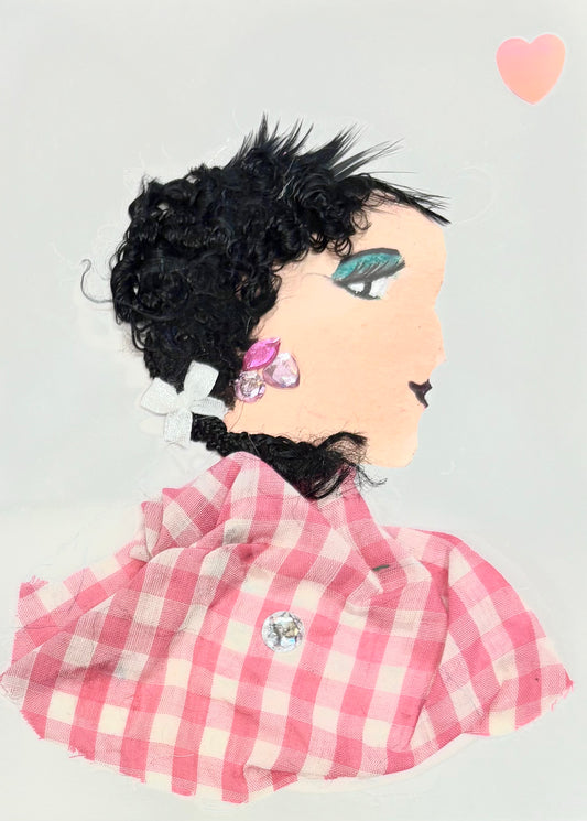Handmade card featuring a collage of a woman in profile facing right. She has textured black hair made from curly material and wears a pink and silver decorative earring. Her outfit is crafted from pink and white gingham fabric, with a small embellishment at the chest. A pink heart is placed in the top right corner against a light grey background.
