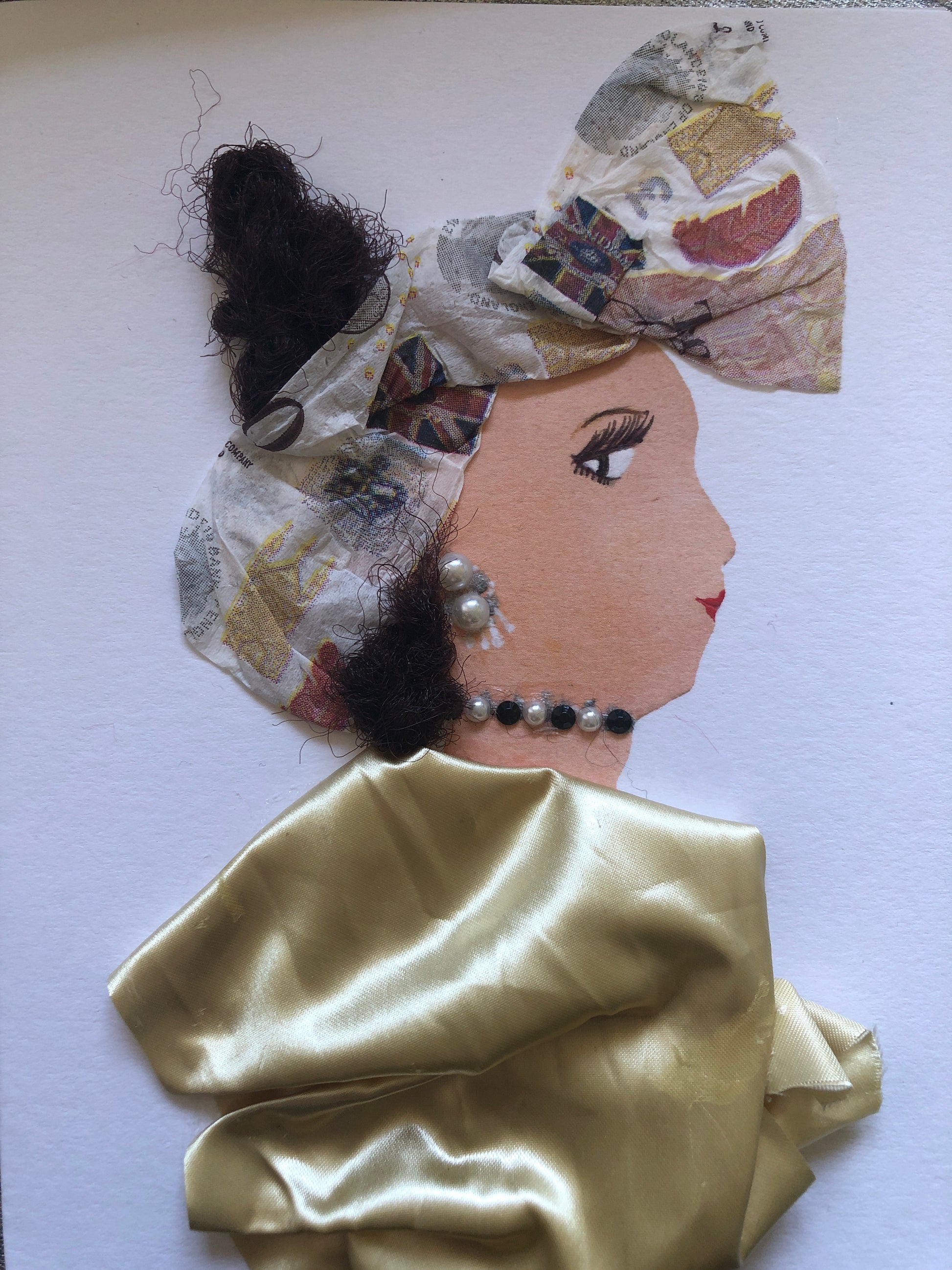 I handmade this card of a woman named Moni Milly. She's adorned in a shimmering gold fabric with soft folds and wears a bow-like headwrap made from patterned paper. Her pearl accessories, earrings and necklace, add a classic touch to her graceful look.