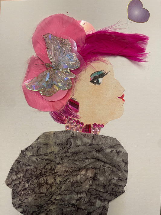Handmade card of a woman with hot pink feathered hair, a large pink flower with a silver butterfly, and pink gem earrings and necklace. She wears a flowing grey-black patterned dress and a purple heart sticker floats nearby.