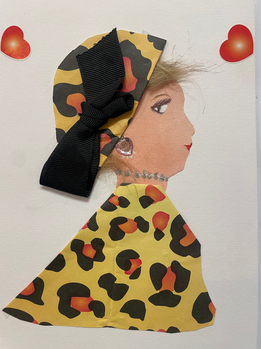 A handmade card of a woman in profile with a leopard print outfit and matching headwrap, adorned with a large black ribbon bow. She wears a crystal-shaped earring and is surrounded by two red heart stickers in the top corners