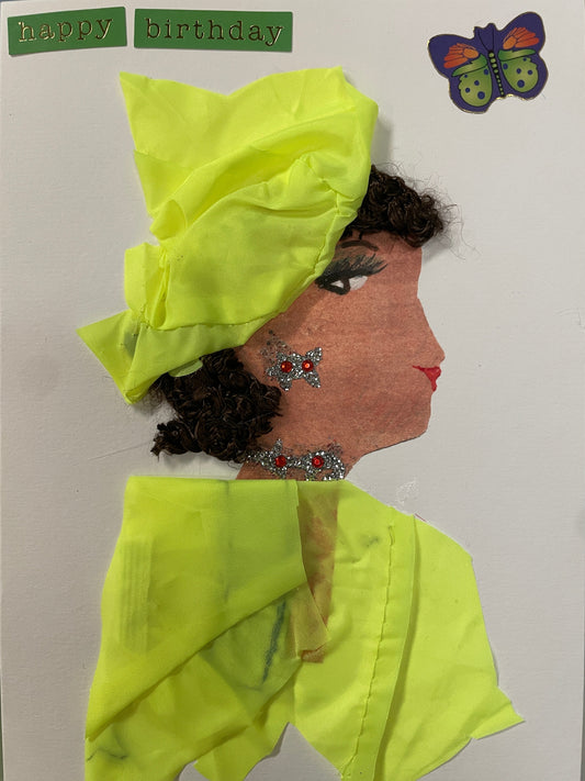 This is a handmade card of a woman named Nylssa Newbury wearing a bright yellow head wrap and outfit with silver and red embellishments, and a butterfly sticker  in the top right corner. In the top left, you can see a sticker saying "happy birthday"