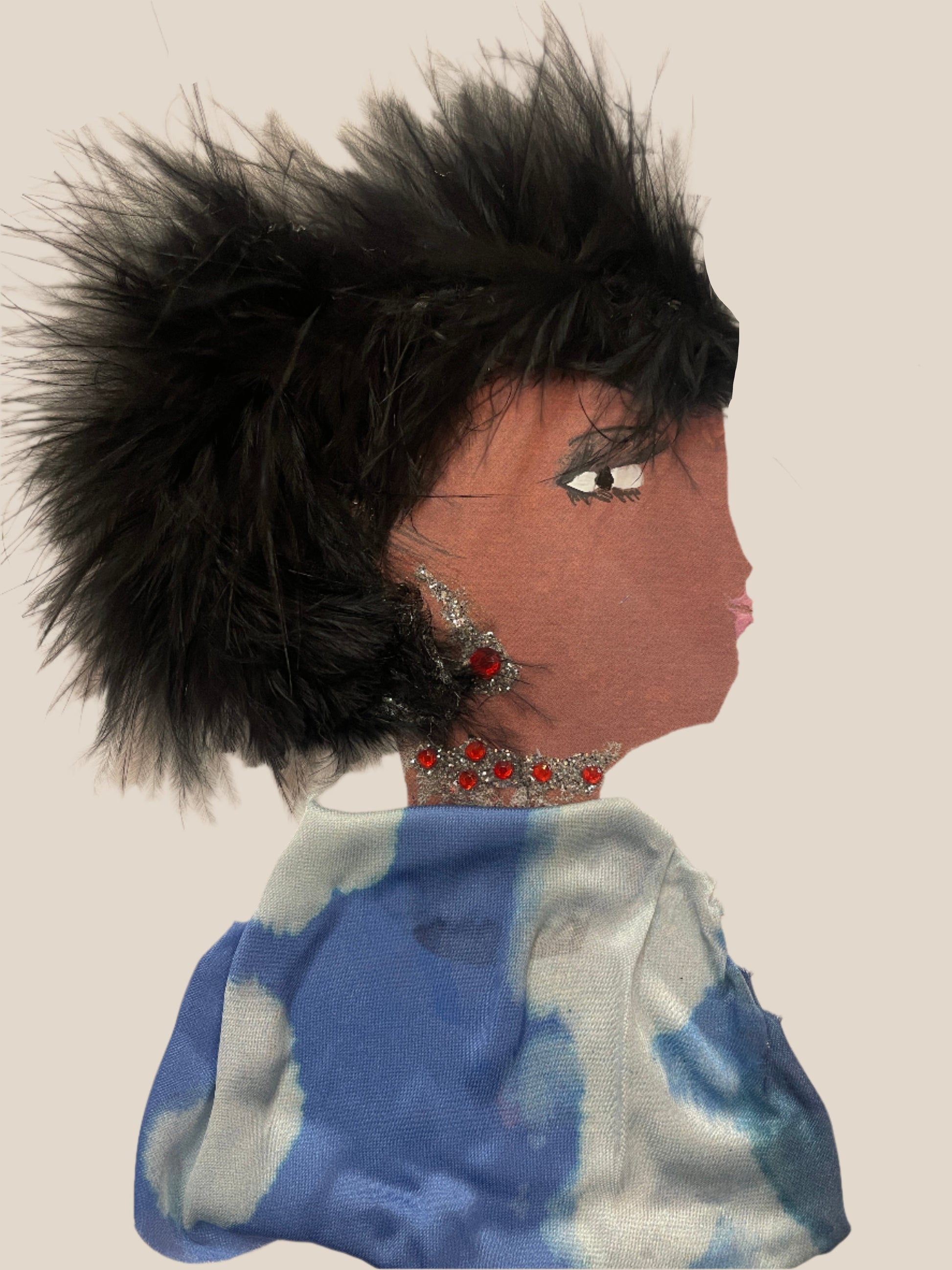 This is a handmade card of a woman named Olivia Overground. She has a large feathered black hairstyle, wears sparkly red jewellery and a flowing blue-patterned fabric.