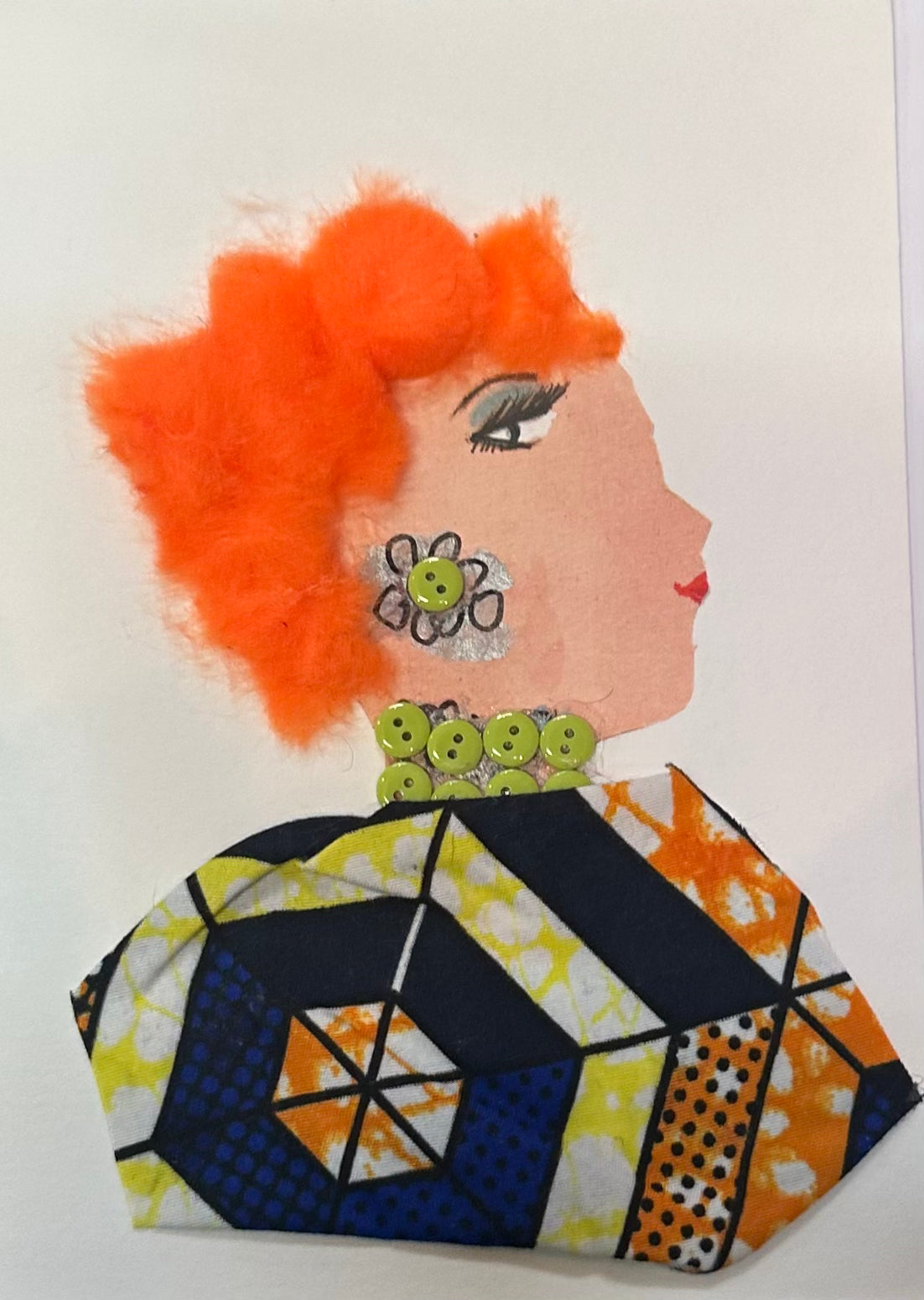 A handmade portrait of “Orange Operator,” featuring fluffy bright orange hair, a green flower earring, a green beaded collar, and a geometric patterned cloak in blue, yellow, and orange tones.