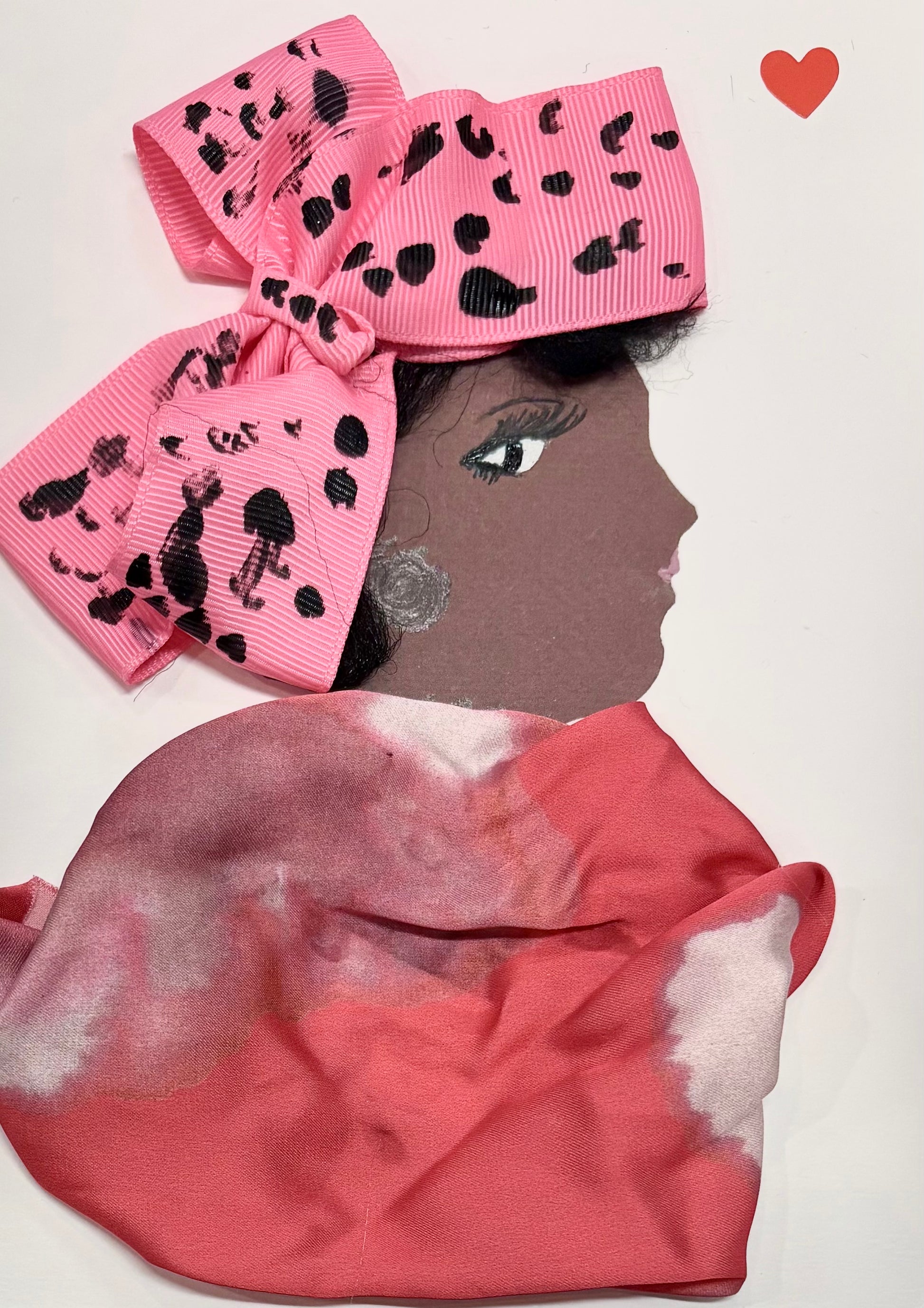 A woman wears a large pink bow with black polkadots on her head. Her blouse is a coral pink with some white accents. There is a small red heart in the top right corner.
