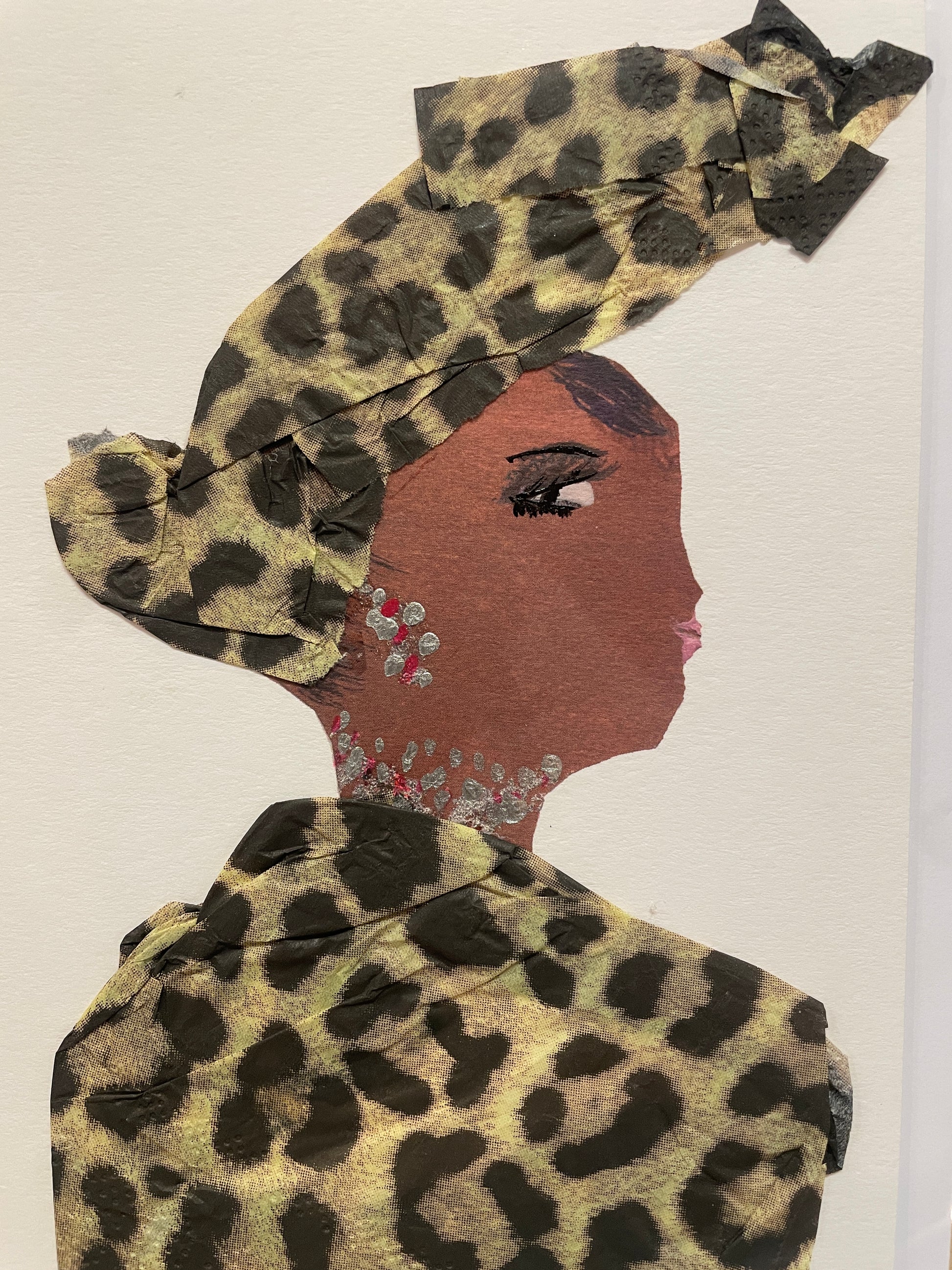 A handmade card of a woman named Peckham Pearl in profile wearing a muted brown and black leopard-patterned outfit and matching headwrap. Her jewellery is made of pink gems and silver accents.